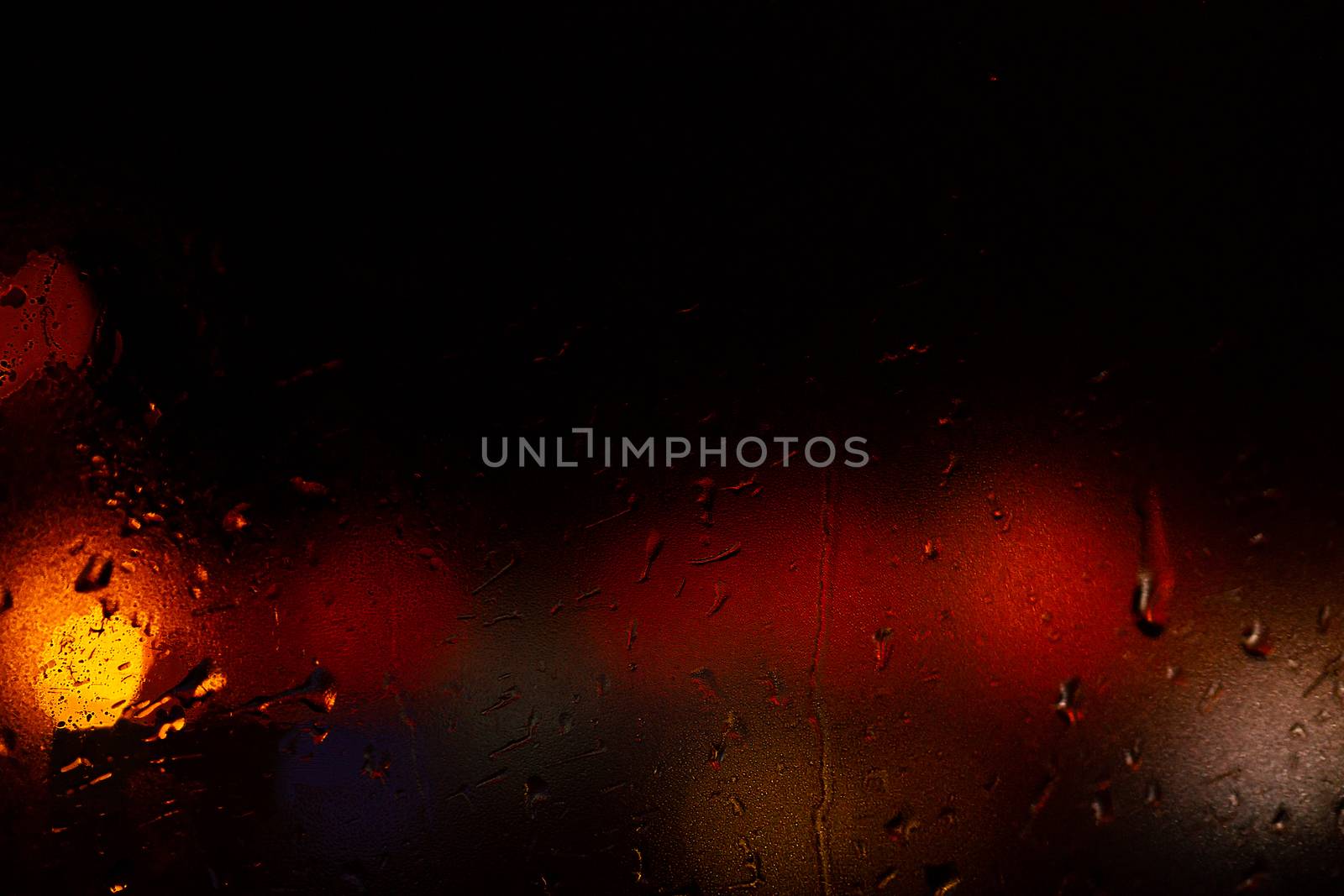 Night colorful big city lights through car windshield.

Light are defocused and blurred. Focus on windshield. Underexposed photo.