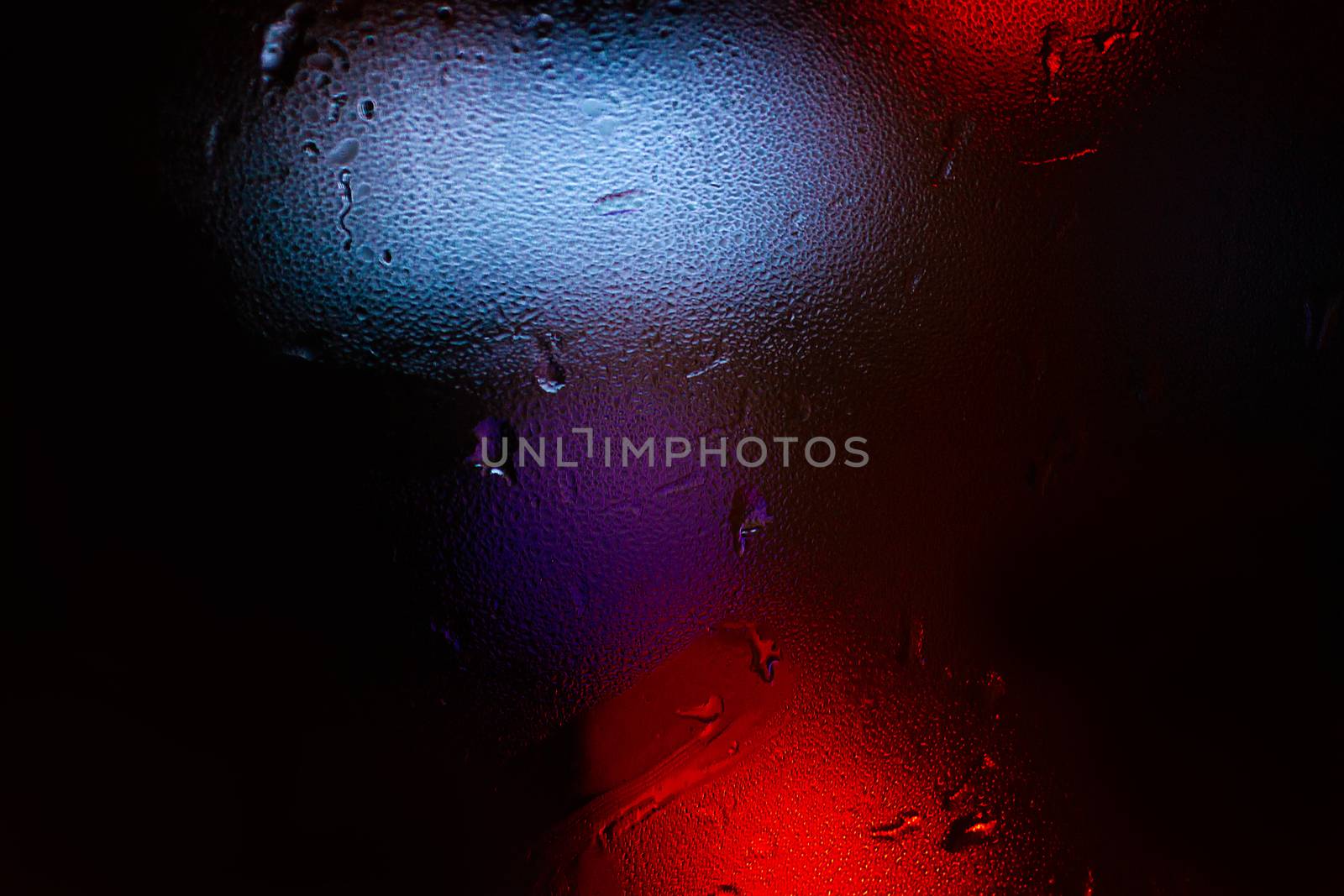 Night colorful big city lights through car windshield.

Light are defocused and blurred. Focus on windshield. Underexposed photo.