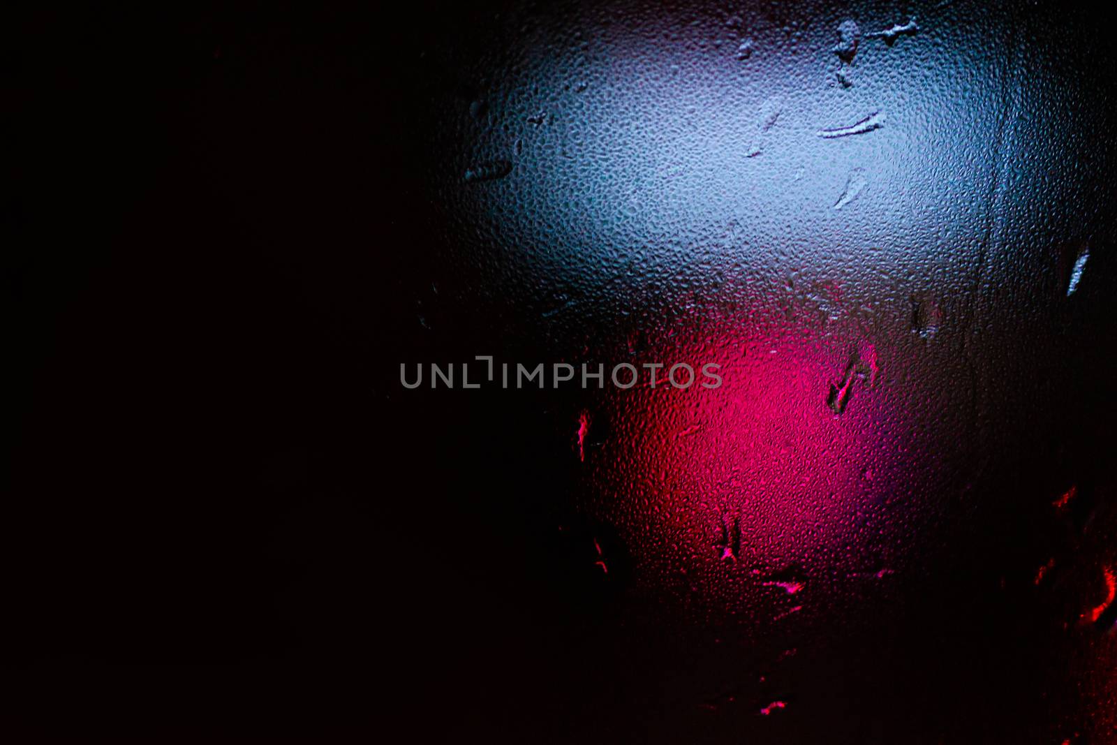 Night colorful big city lights through car windshield.

Light are defocused and blurred. Focus on windshield. Underexposed photo.