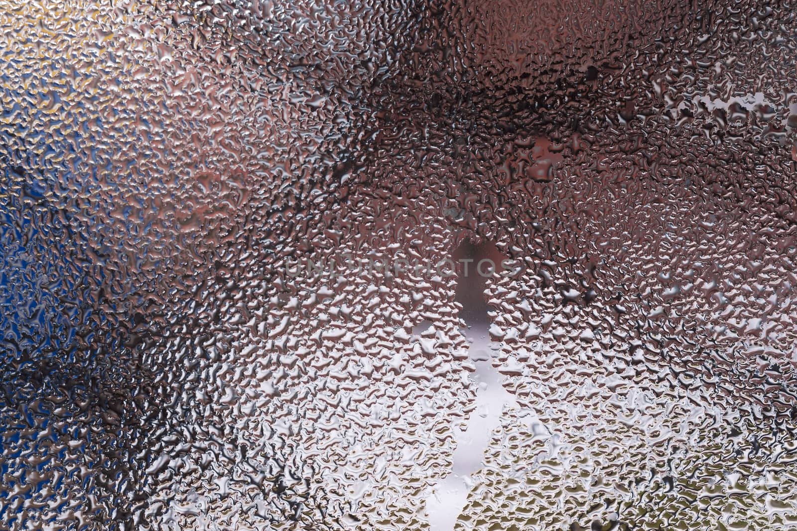 Water drops on glass window close up with blurred background. Drops in macro. Condensate on window closeup. Wet air.