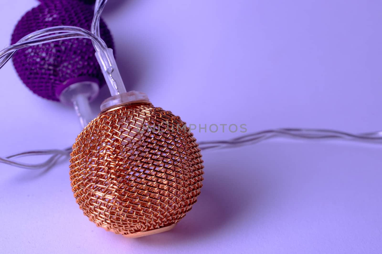 Battery garland with metallic grid balls on white background. Closeup view with blurred background.
