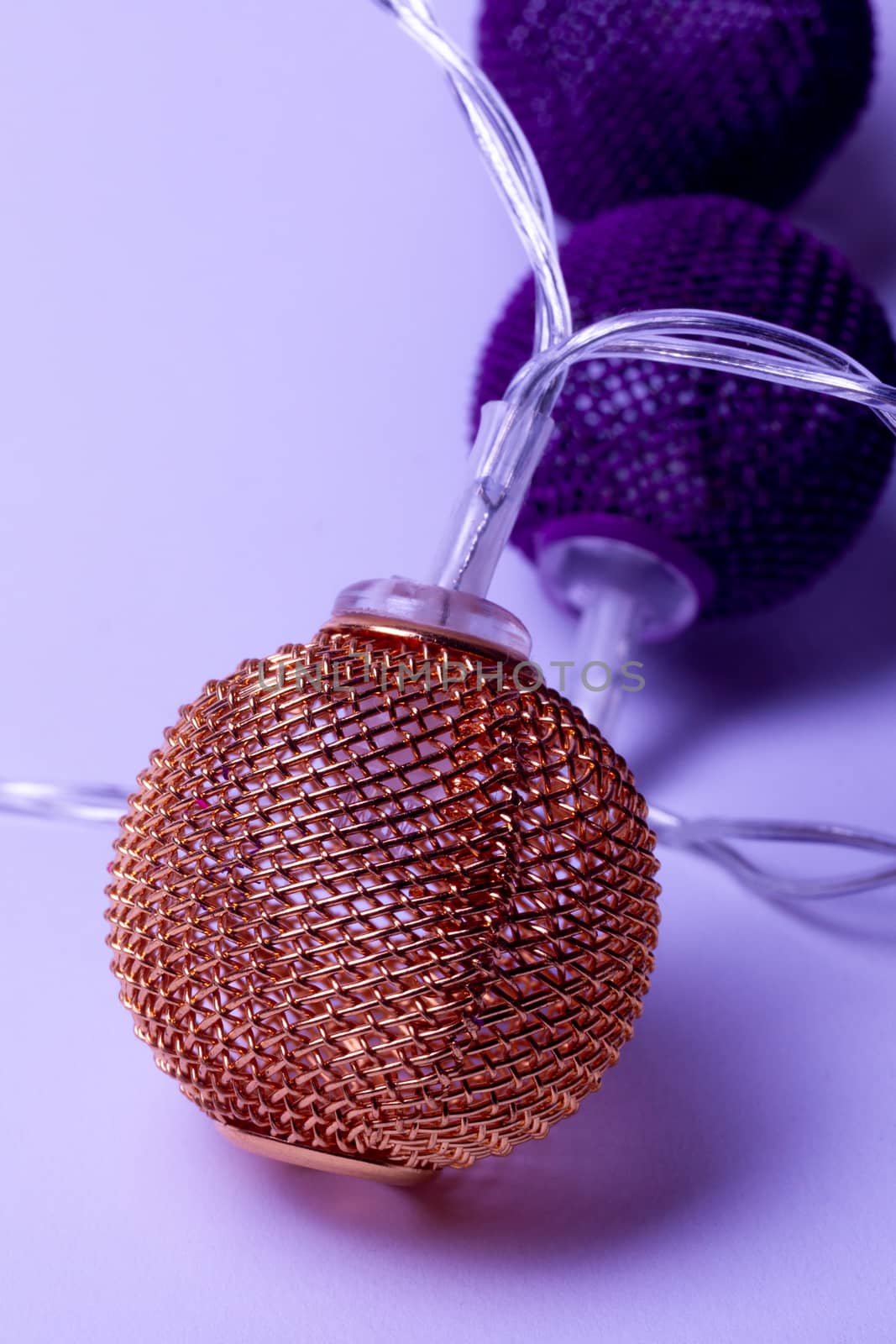 Battery garland with metallic grid balls on white background. Closeup view with blurred background.