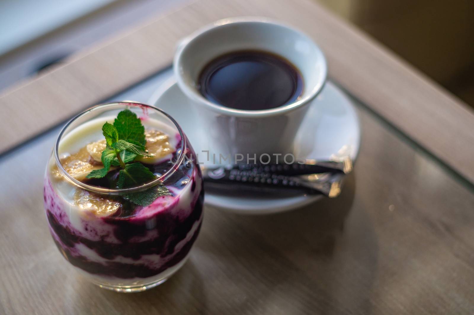 Granola with yogurt and blackberry jam with mint leaf on top and cup of coffee. Blurred background. Healty breakfast. Fitness food.