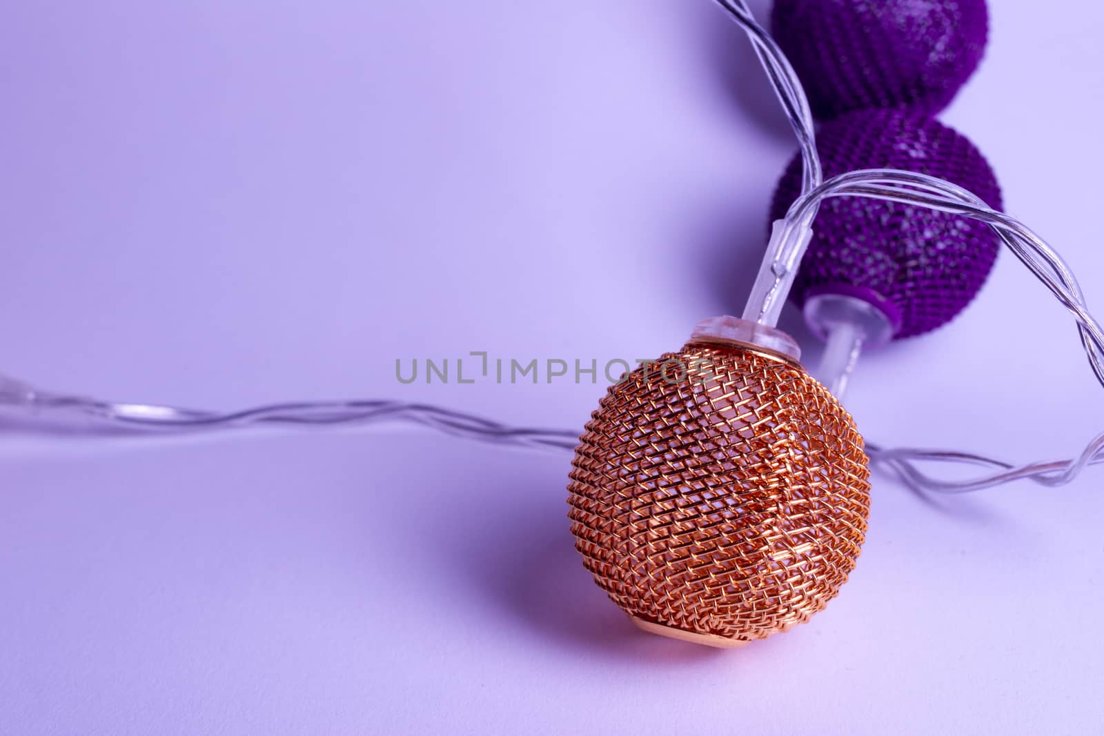 Battery garland with metallic grid balls on white background. Closeup view with blurred background.