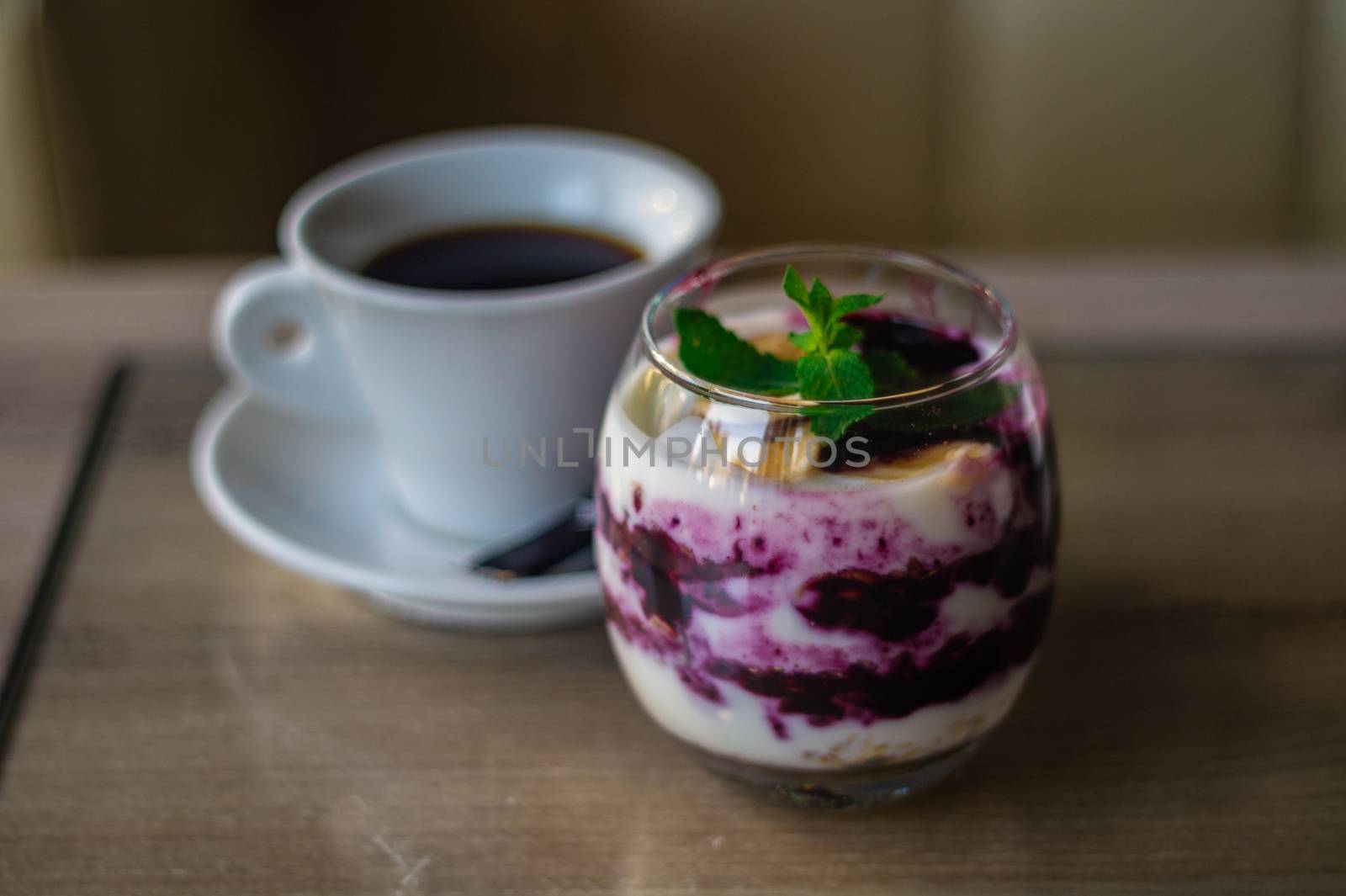 Granola with yogurt and blackberry jam with mint leaf on top and cup of coffee. Blurred background. Healty breakfast. Fitness food.