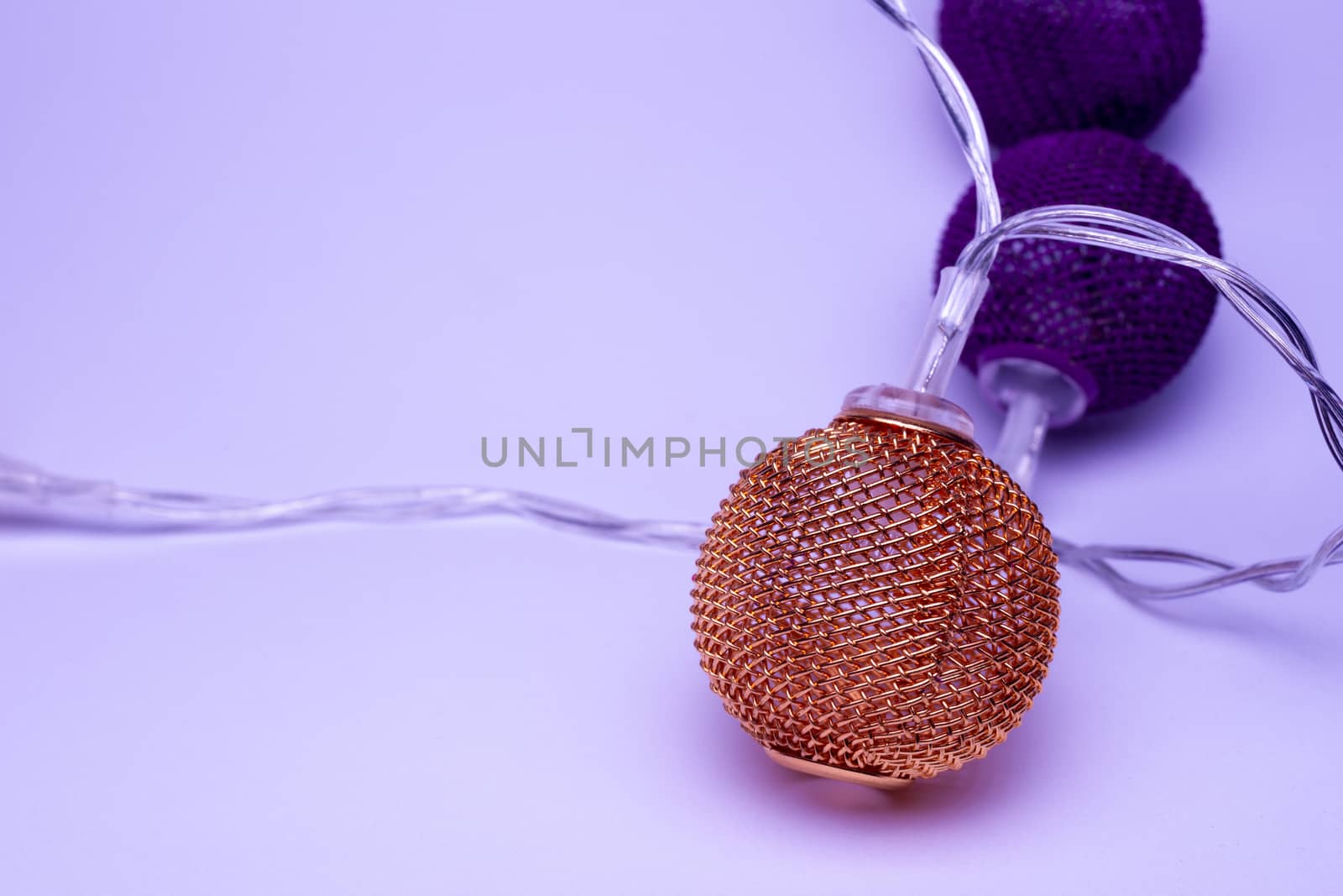 Battery garland with metallic grid balls on white background. Closeup view with blurred background.