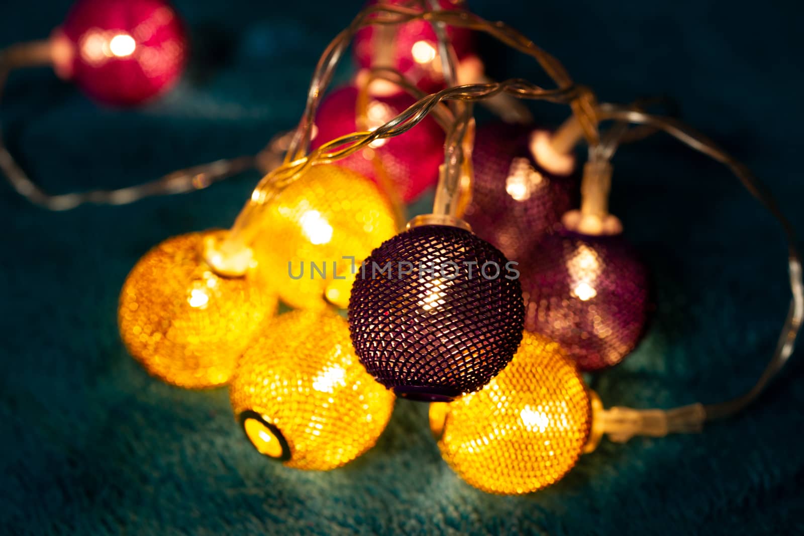 Battery garland with metallic grid balls on blue blanket. Closeup view with blurred background.
