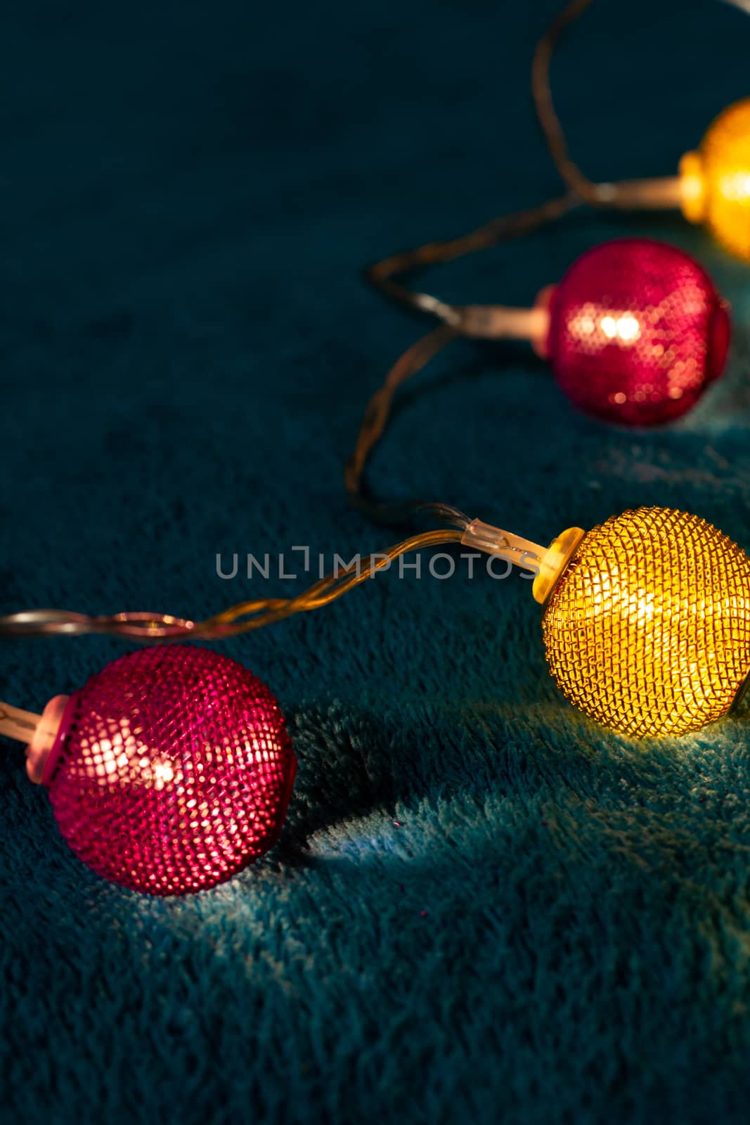 Battery garland with metallic grid balls on blue blanket. Closeup view with blurred background.