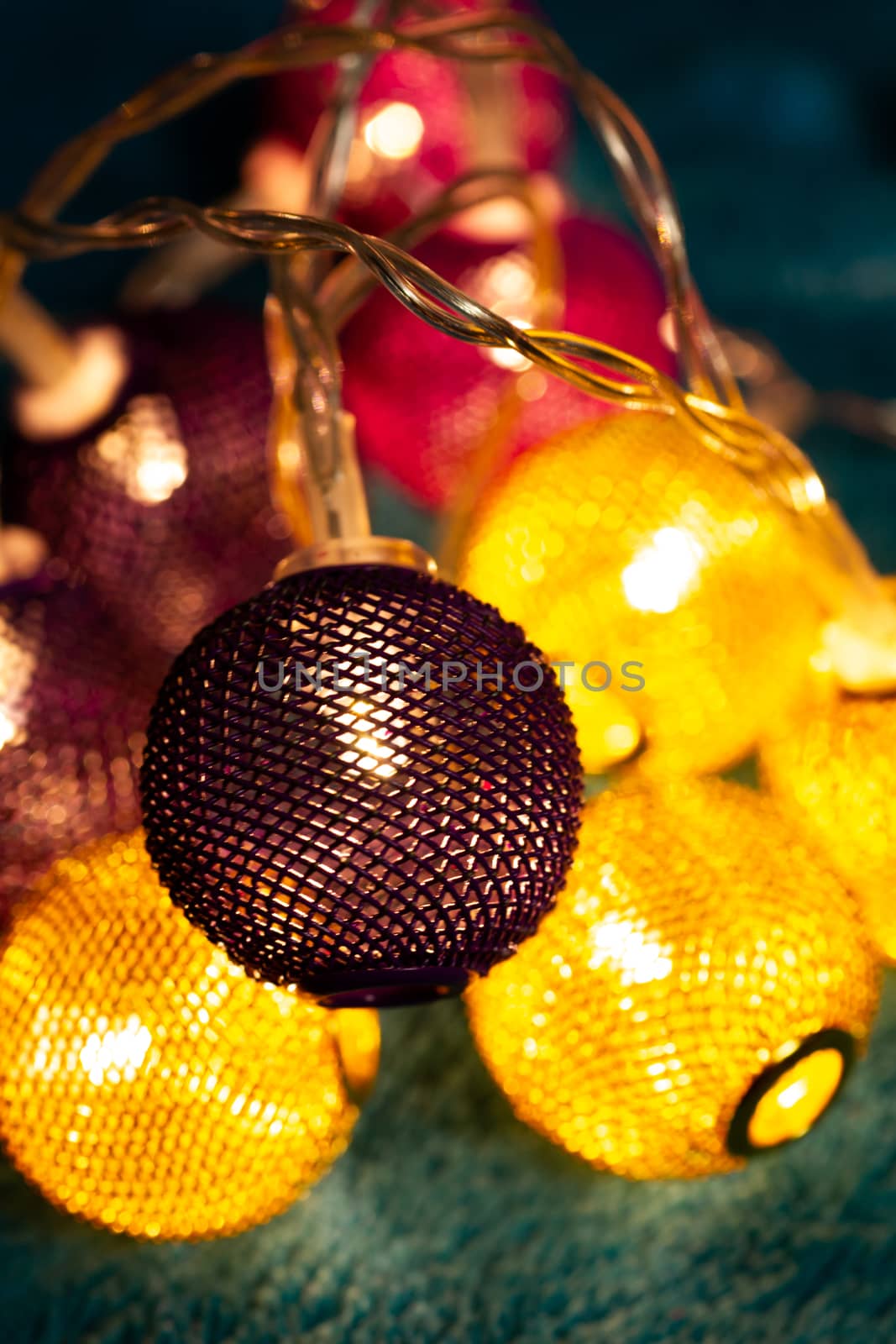 Battery garland with metallic grid balls on blue blanket. Closeup view with blurred background.