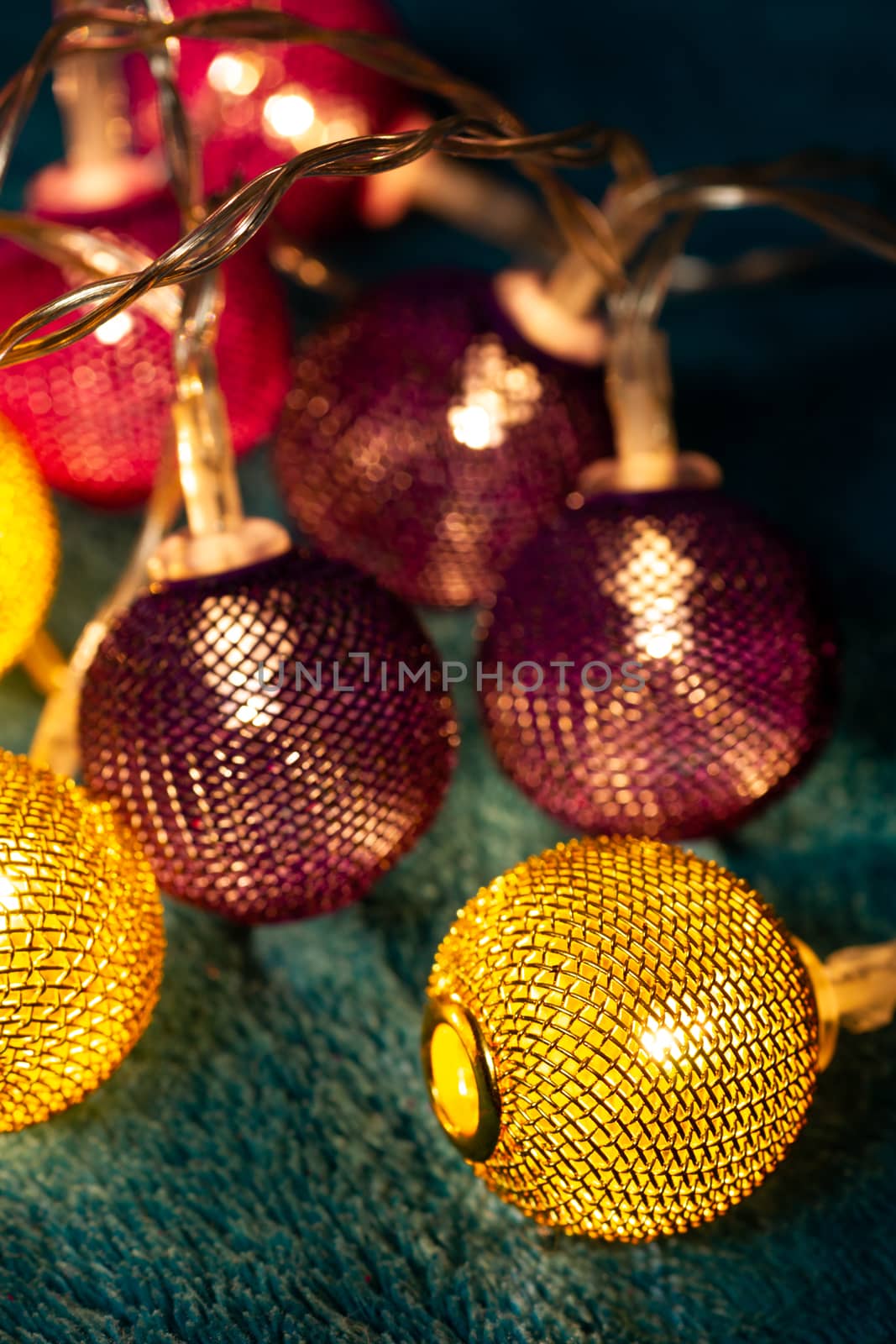 Battery garland with metallic grid balls on blue blanket. Closeup view with blurred background.