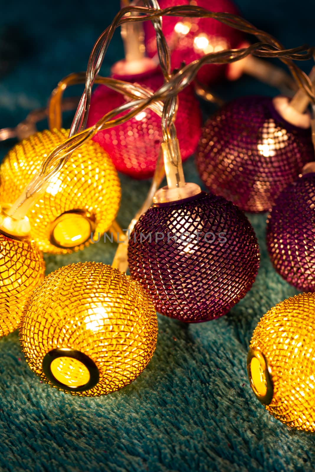 Battery garland with metallic grid balls on blue blanket. Closeup view with blurred background.