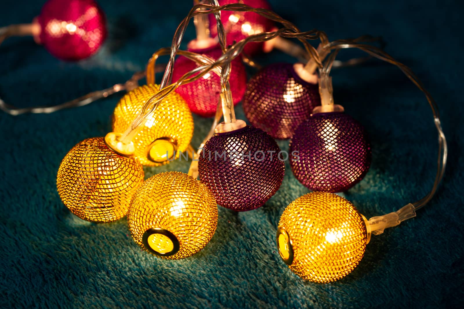 Battery garland with metallic grid balls on blue blanket. Closeup view with blurred background.