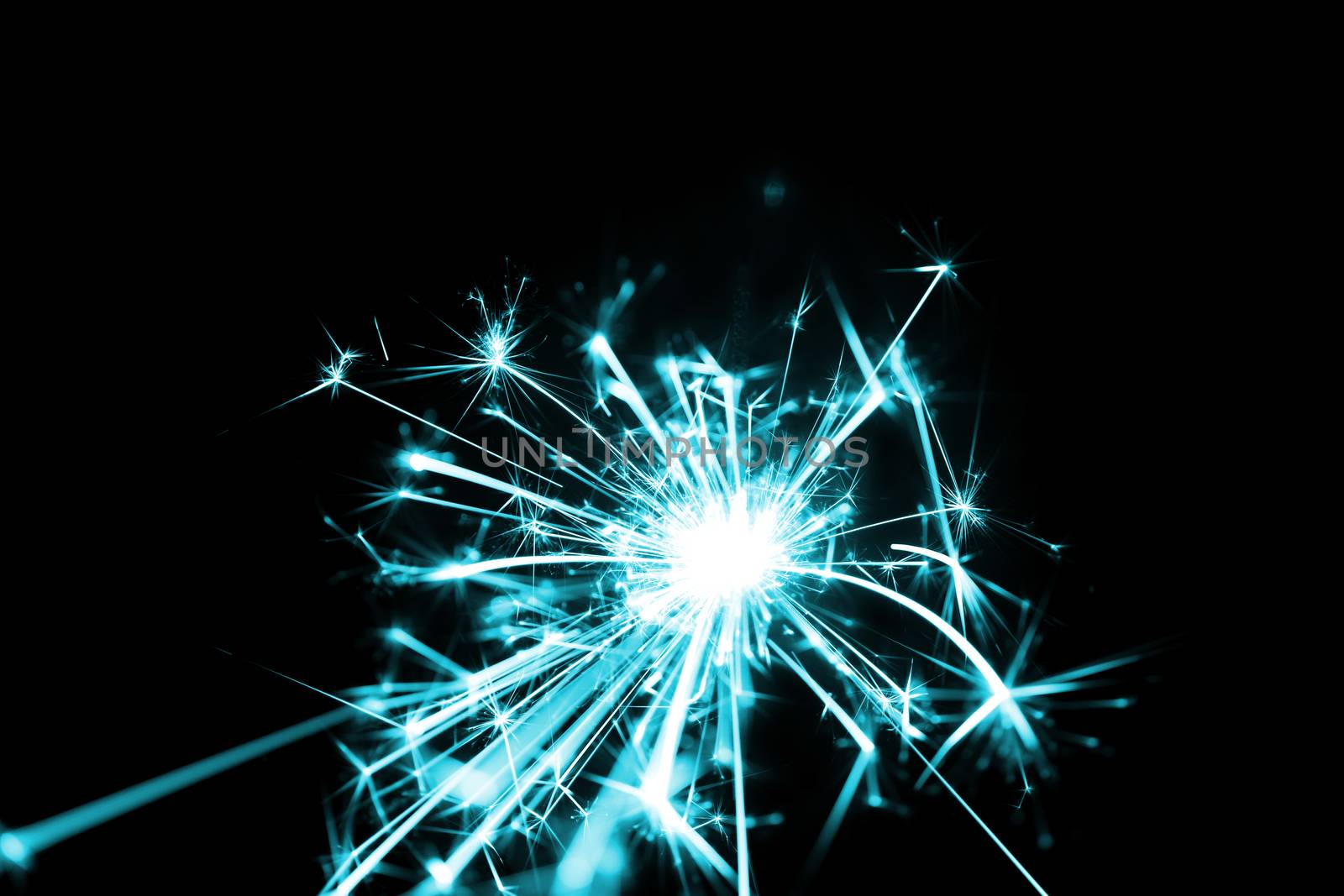 Low light photo of bengali fire isolated on black background with blue toning. A lot of light and sparks. Underexposed photo.