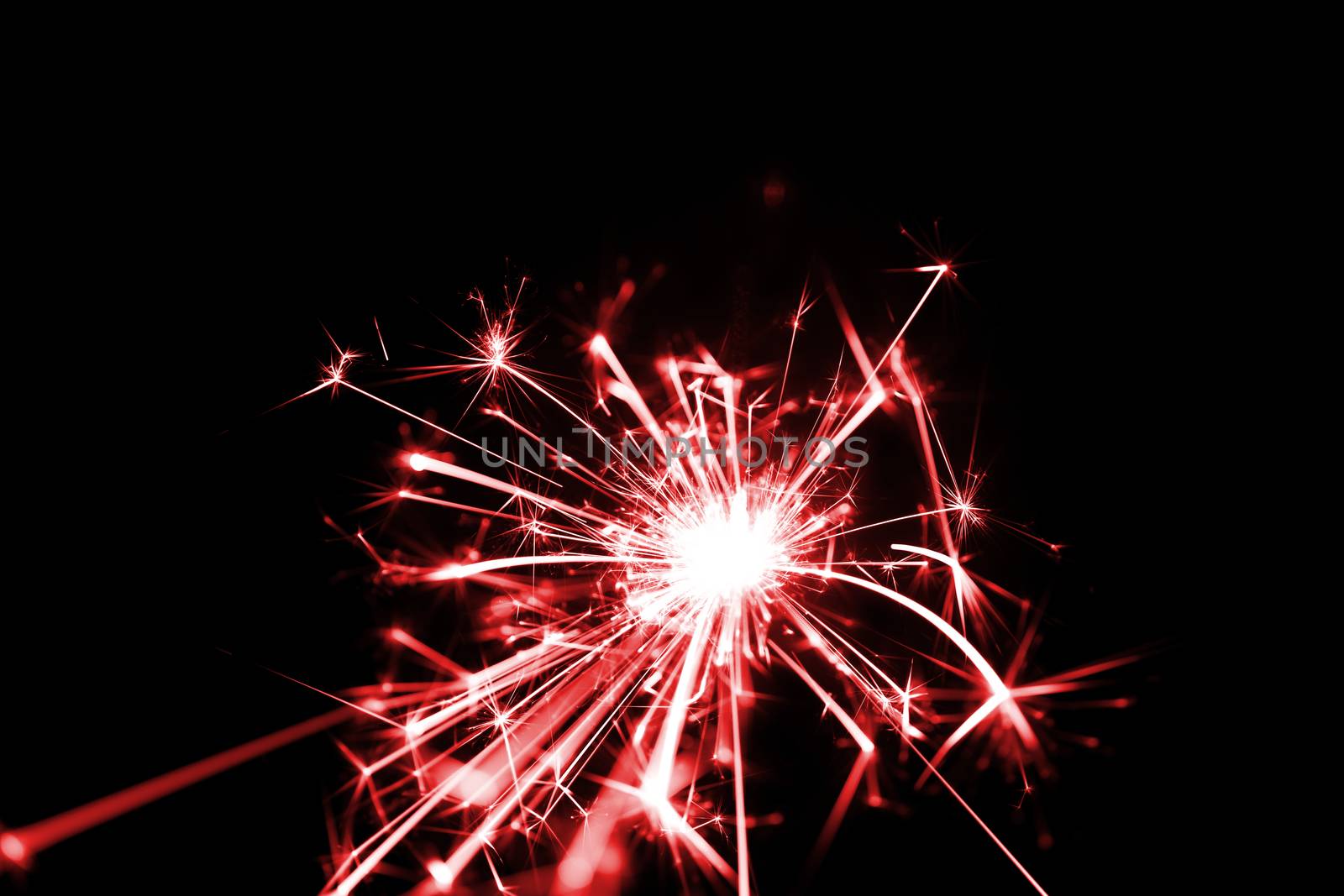 Low light photo of bengali fire isolated on black background with red toning. A lot of light and sparks. Underexposed photo.