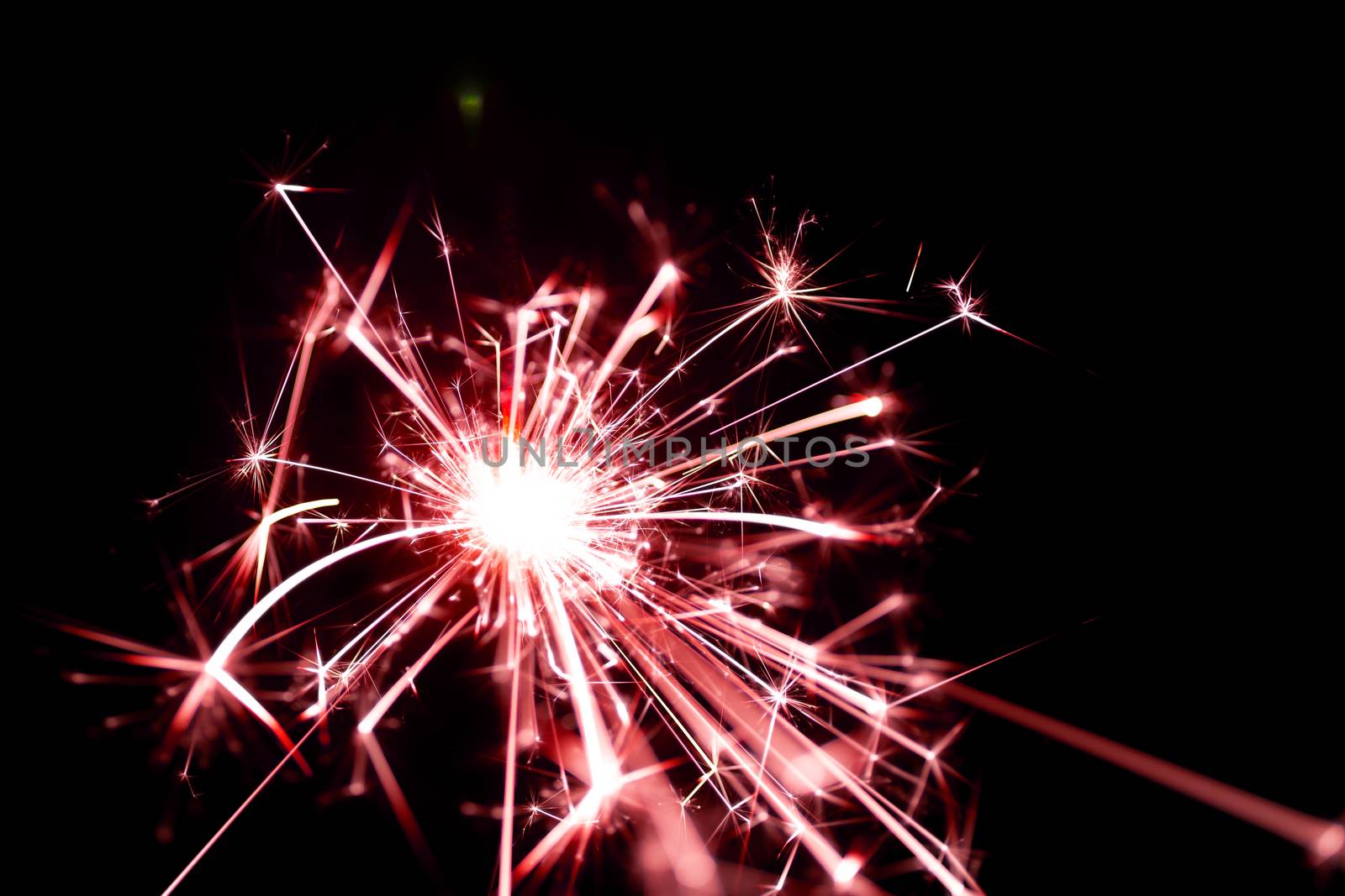 Low light photo of bengali fire isolated on black background with red toning. A lot of light and sparks. Underexposed photo.