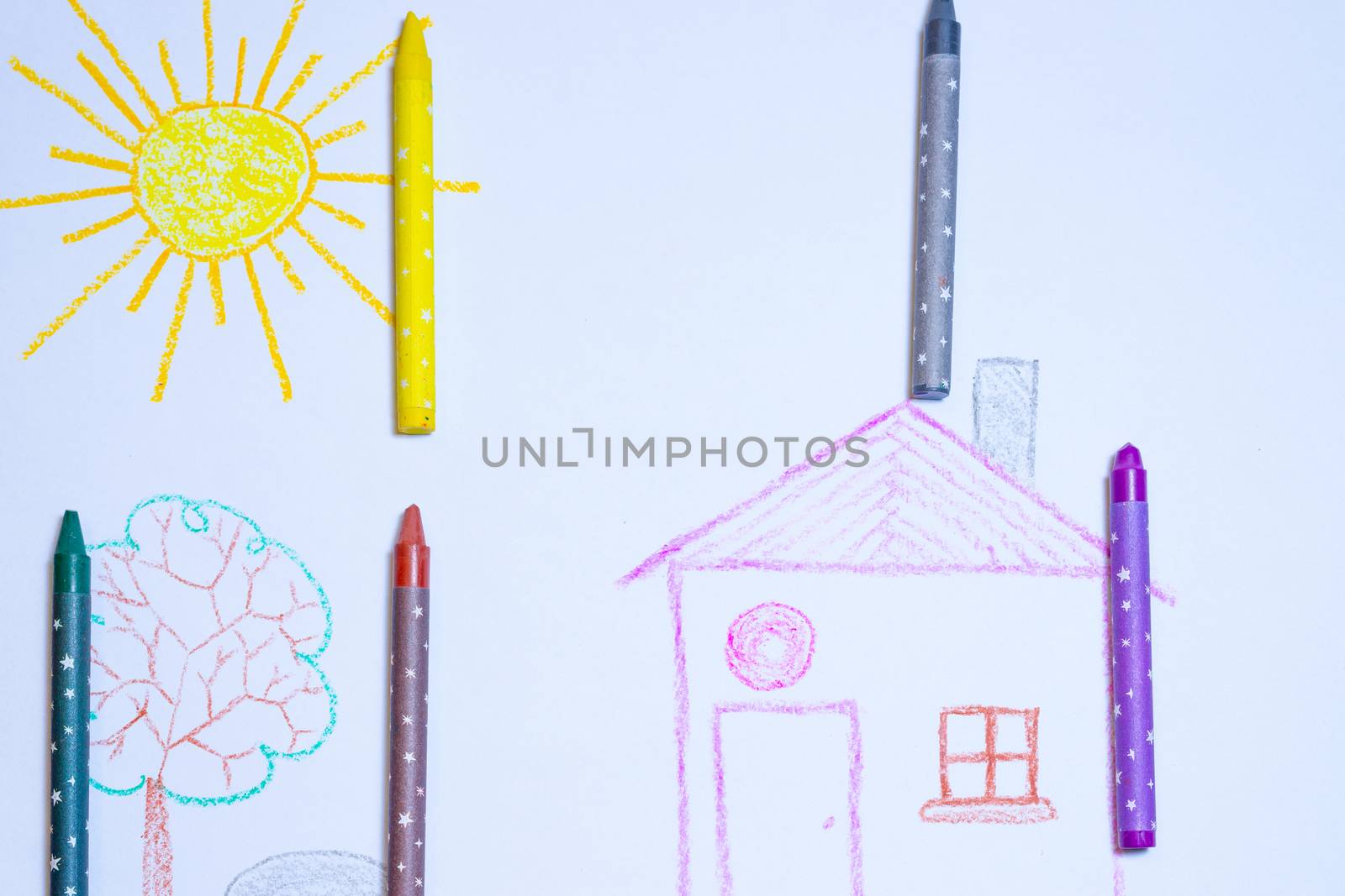 Children`s drawing of house, tree, sun and rock on white paper with wax pencils. Kindergarten age drawings.
