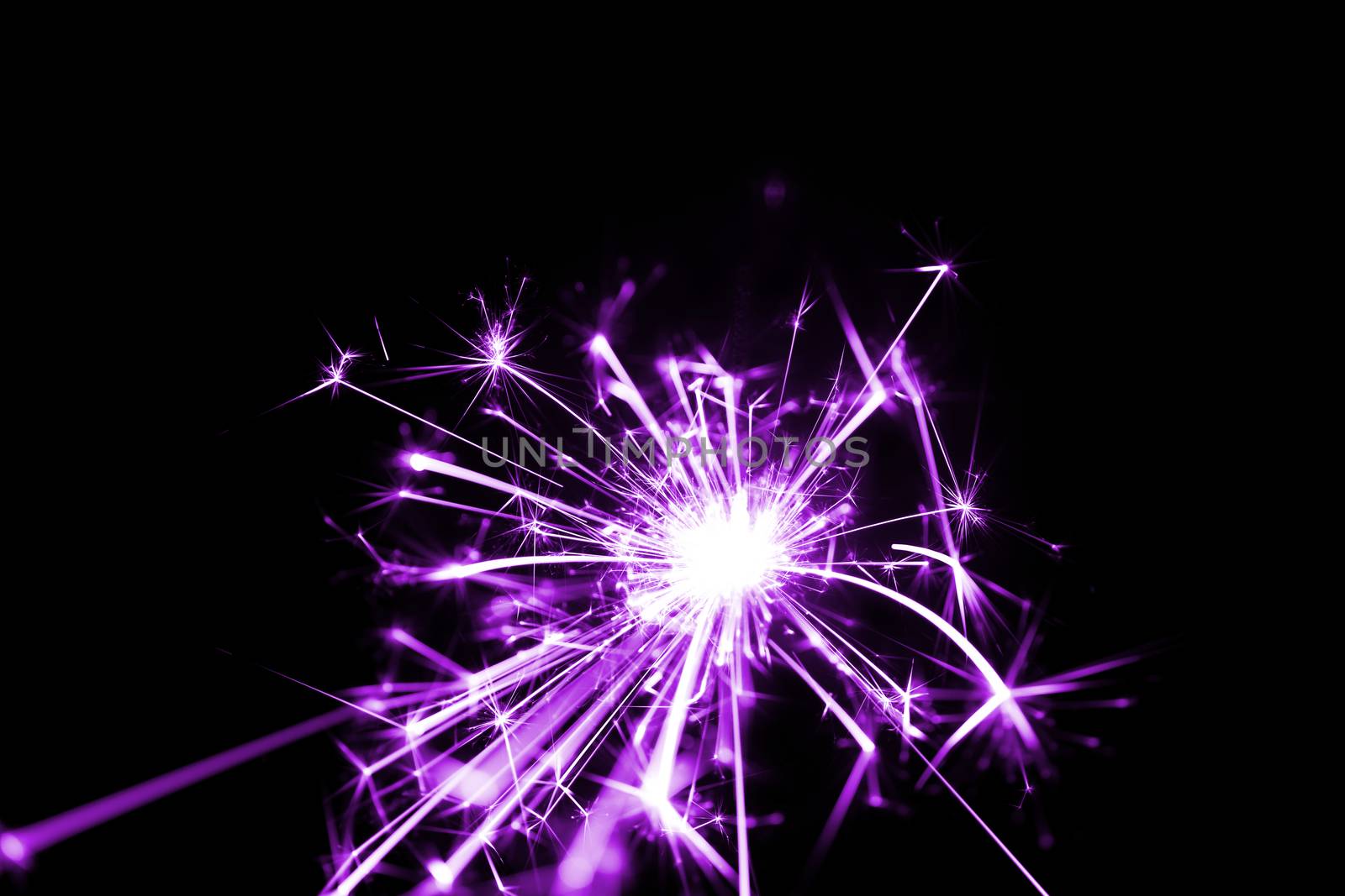 Low light photo of bengali fire isolated on black background with purple toning. A lot of light and sparks. Underexposed photo.