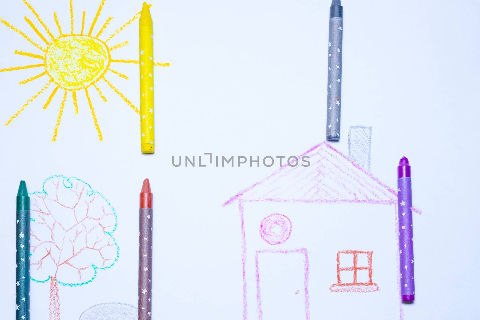 Children`s drawing of house, tree, sun and rock on white paper with wax pencils. Kindergarten age drawings.