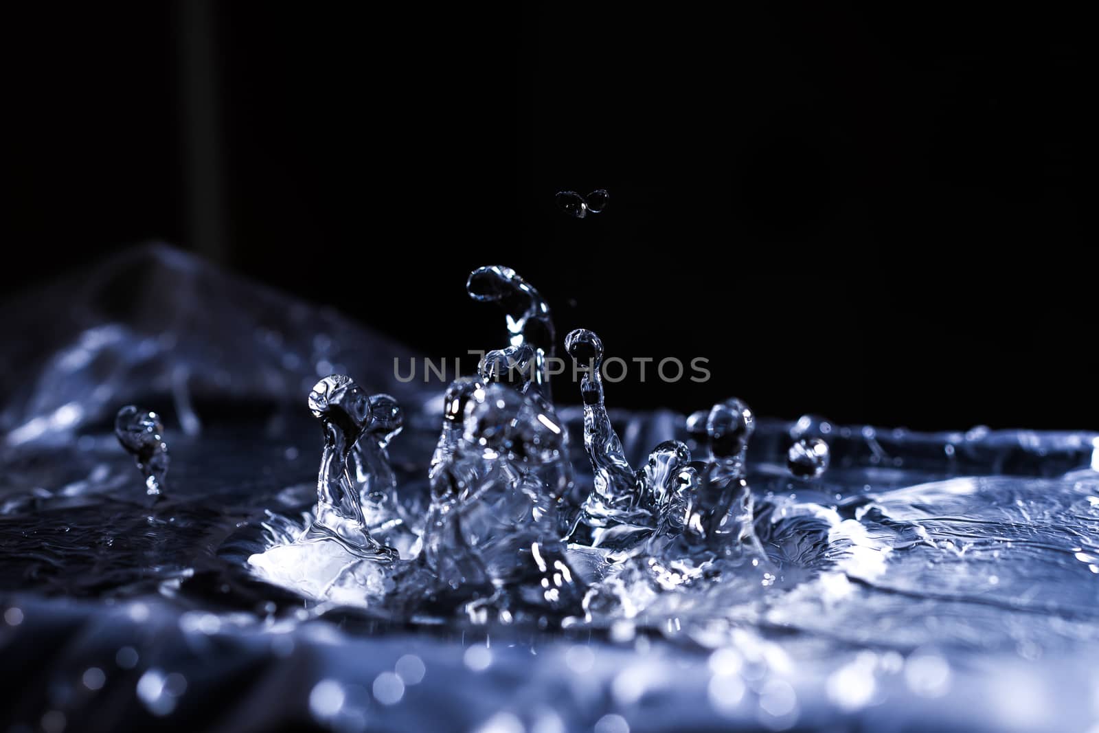 Water drops splashing on acoustic membrane. A lot of drops in air. High frequency of sound waves. Water cloud small drops. Frozen time shot.