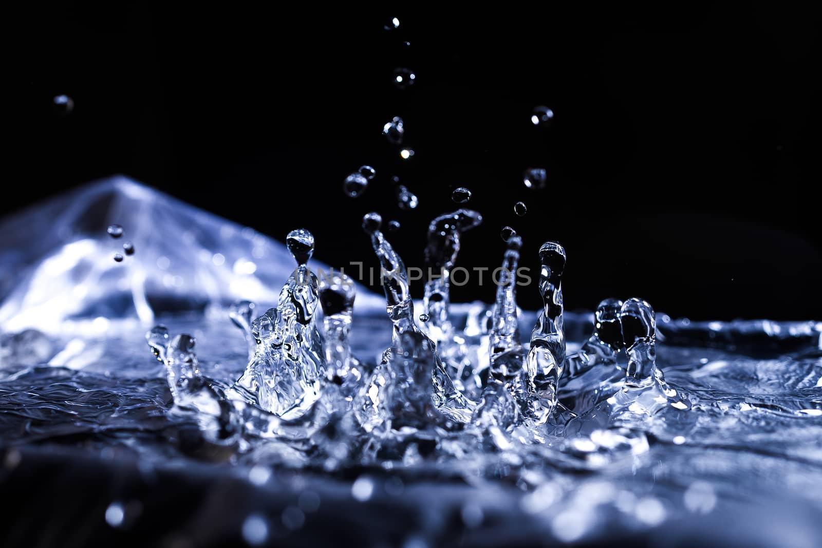 Water drops splashing on acoustic membrane. A lot of drops in air. High frequency of sound waves. Water cloud small drops. Frozen time shot.