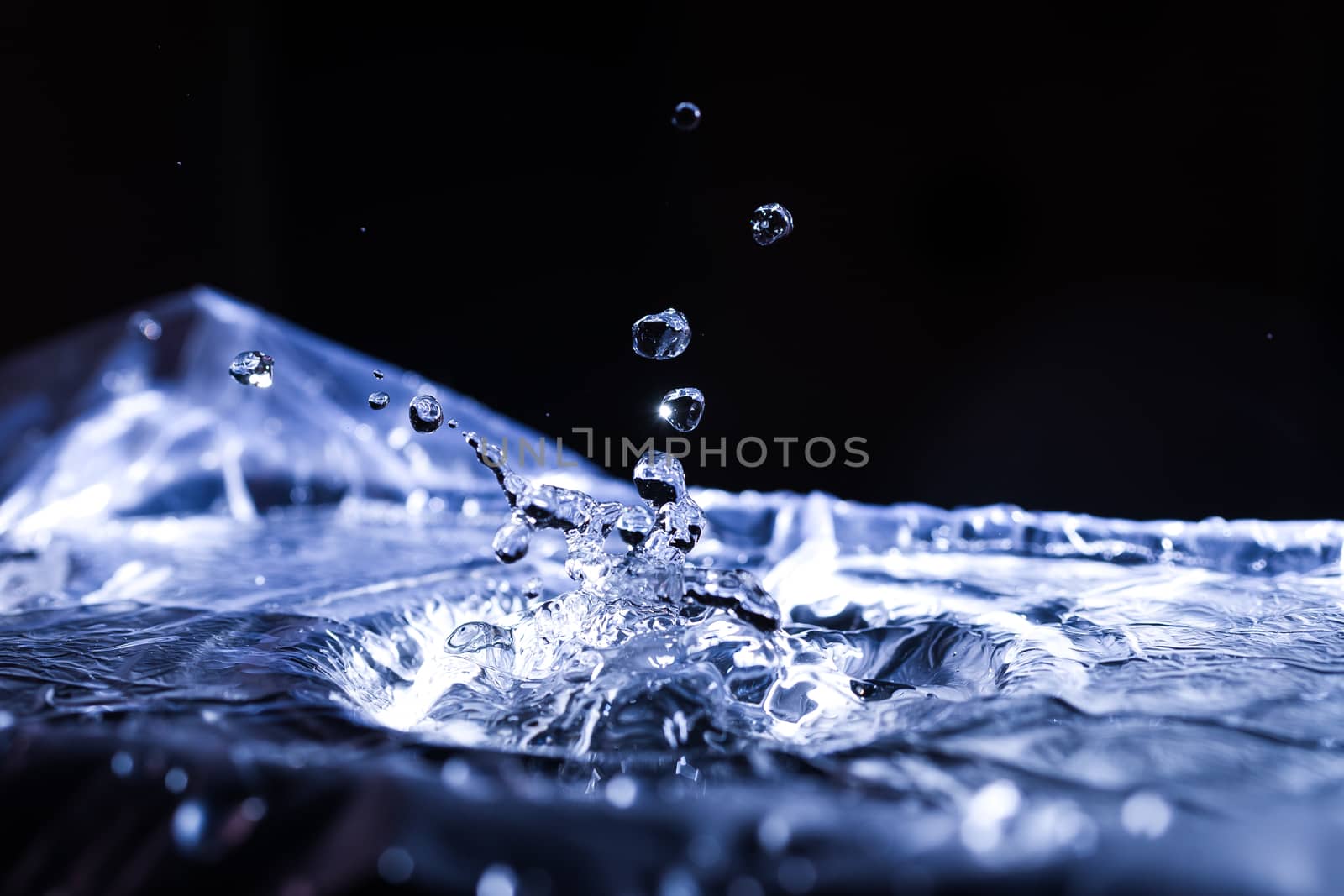 Water drops splashing on acoustic membrane. A lot of drops in air. High frequency of sound waves. Water cloud small drops. Frozen time shot.