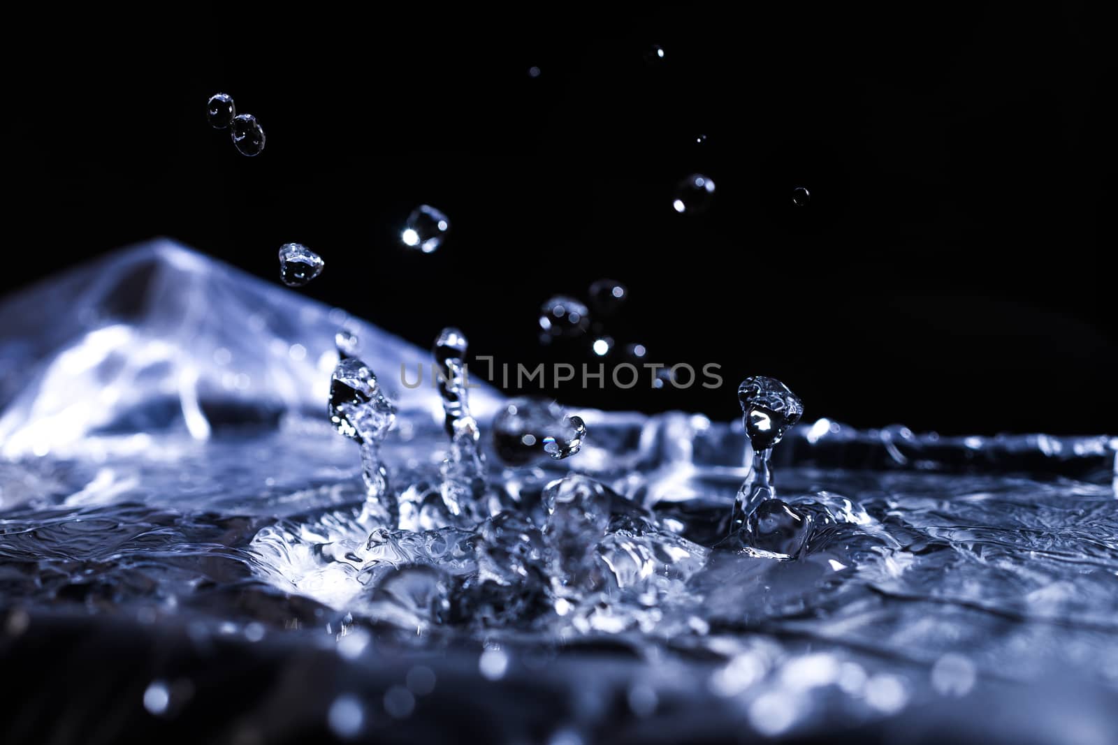 Water drops splashing on acoustic membrane. A lot of drops in air. High frequency of sound waves. Water cloud small drops. Frozen time shot.
