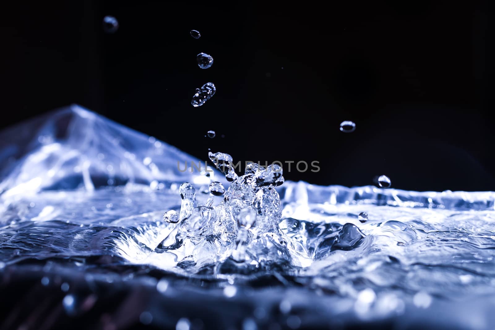 Water drops splashing on acoustic membrane. A lot of drops in air. High frequency of sound waves. Water cloud small drops. Frozen time shot. 