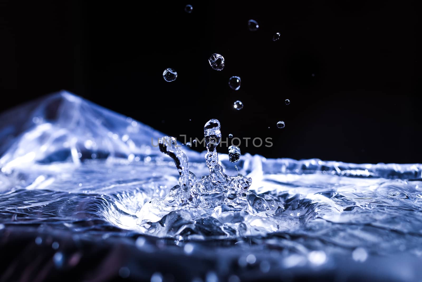 Water drops splashing on acoustic membrane. A lot of drops in air. High frequency of sound waves. Water cloud small drops. Frozen time shot. 