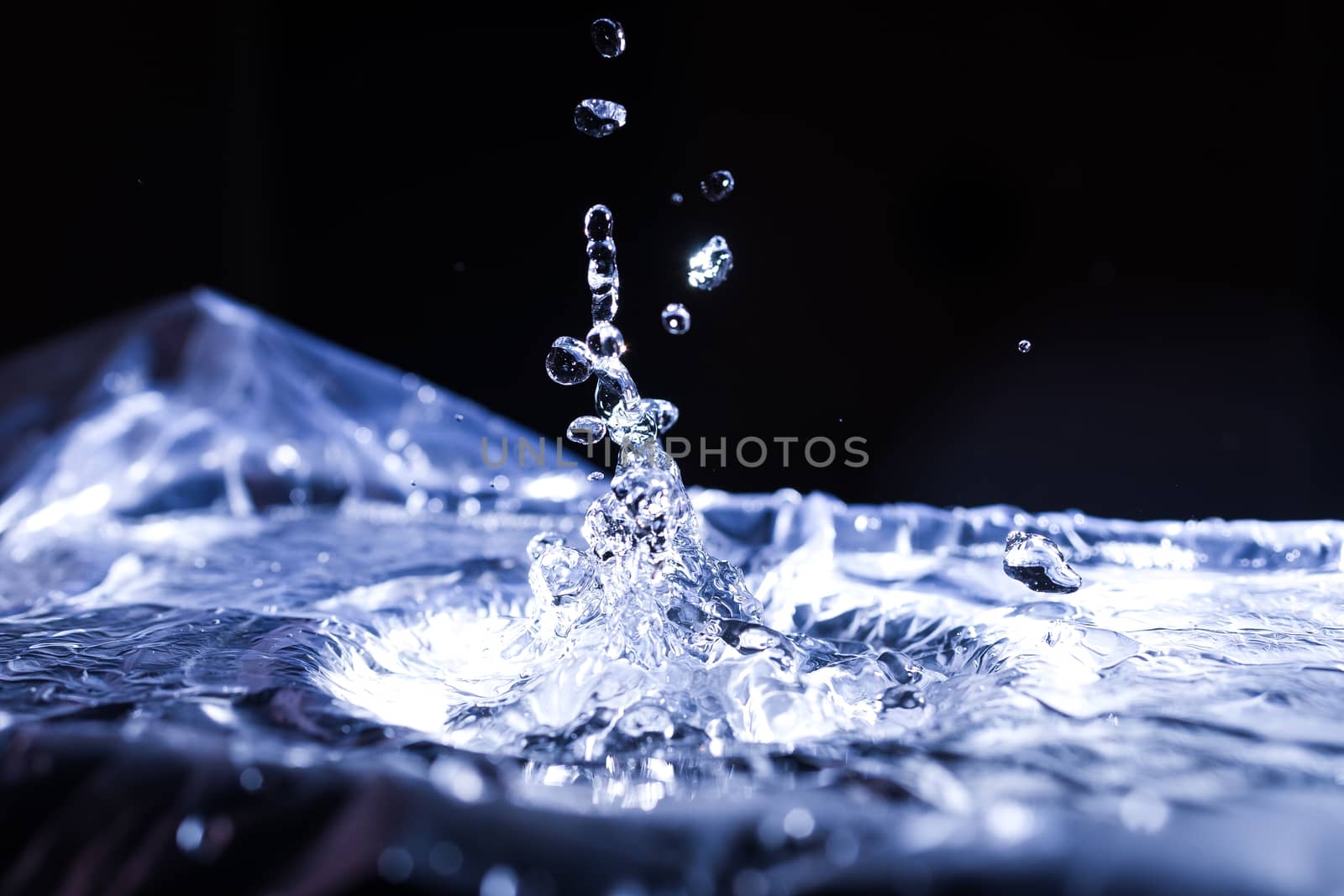 Water drops splashing on acoustic membrane. A lot of drops in air. High frequency of sound waves. Water cloud small drops. Frozen time shot. 