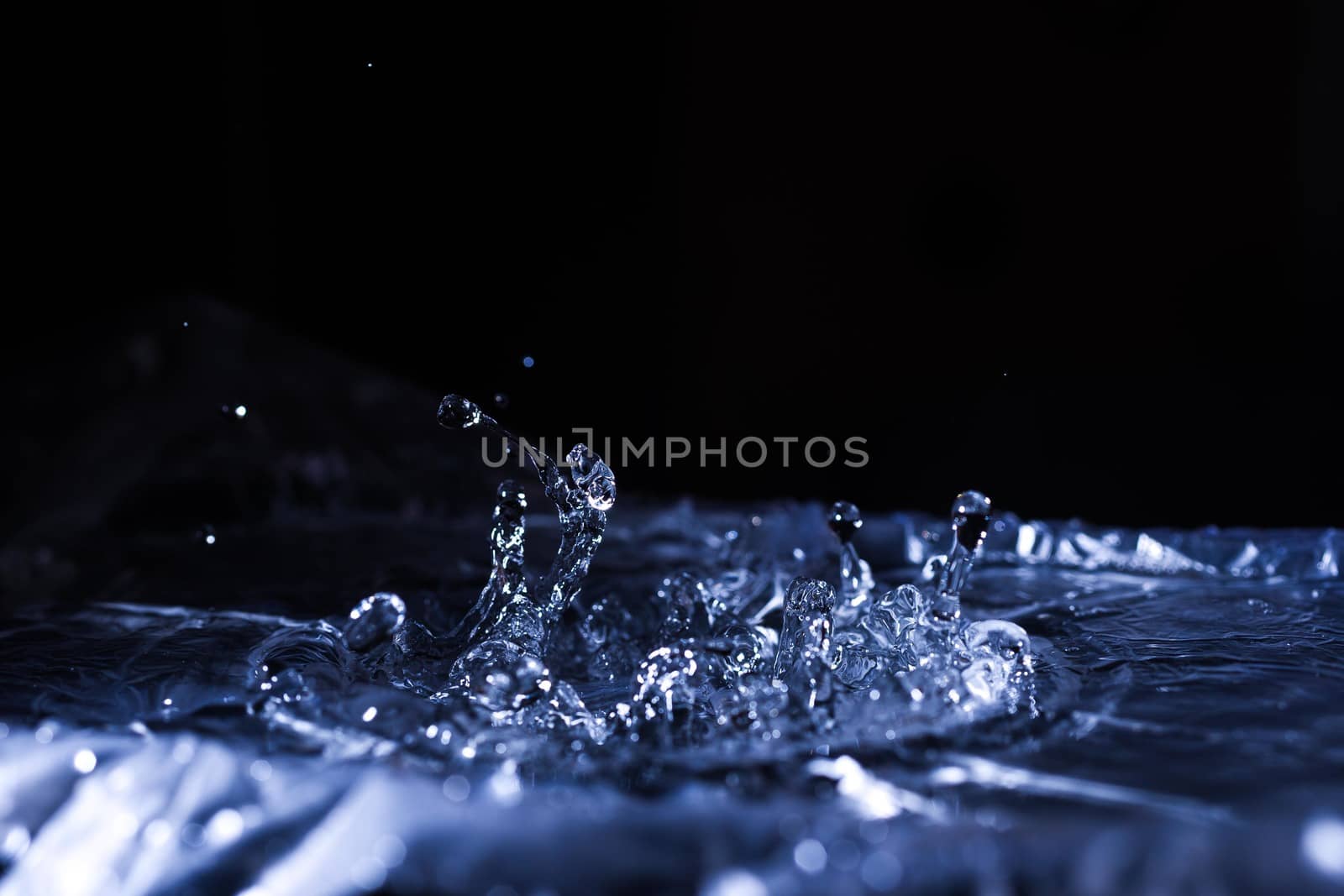 Water drops splashing on acoustic membrane. A lot of drops in air. High frequency of sound waves. Water cloud small drops. Frozen time shot. 