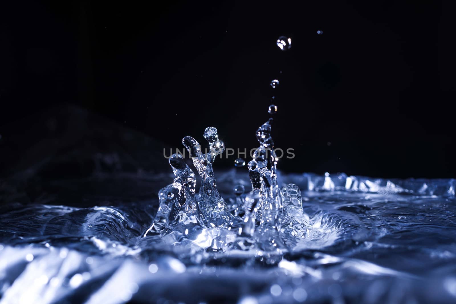Water drops splashing on acoustic membrane. A lot of drops in air. High frequency of sound waves. Water cloud small drops. Frozen time shot.