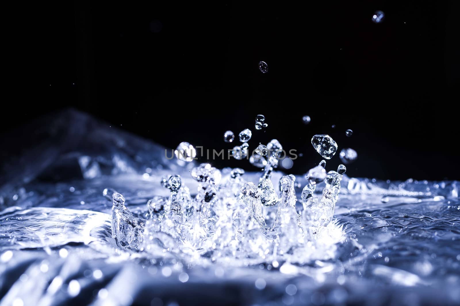 Water drops splashing on acoustic membrane. A lot of drops in air. High frequency of sound waves. Water cloud small drops. Frozen time shot.