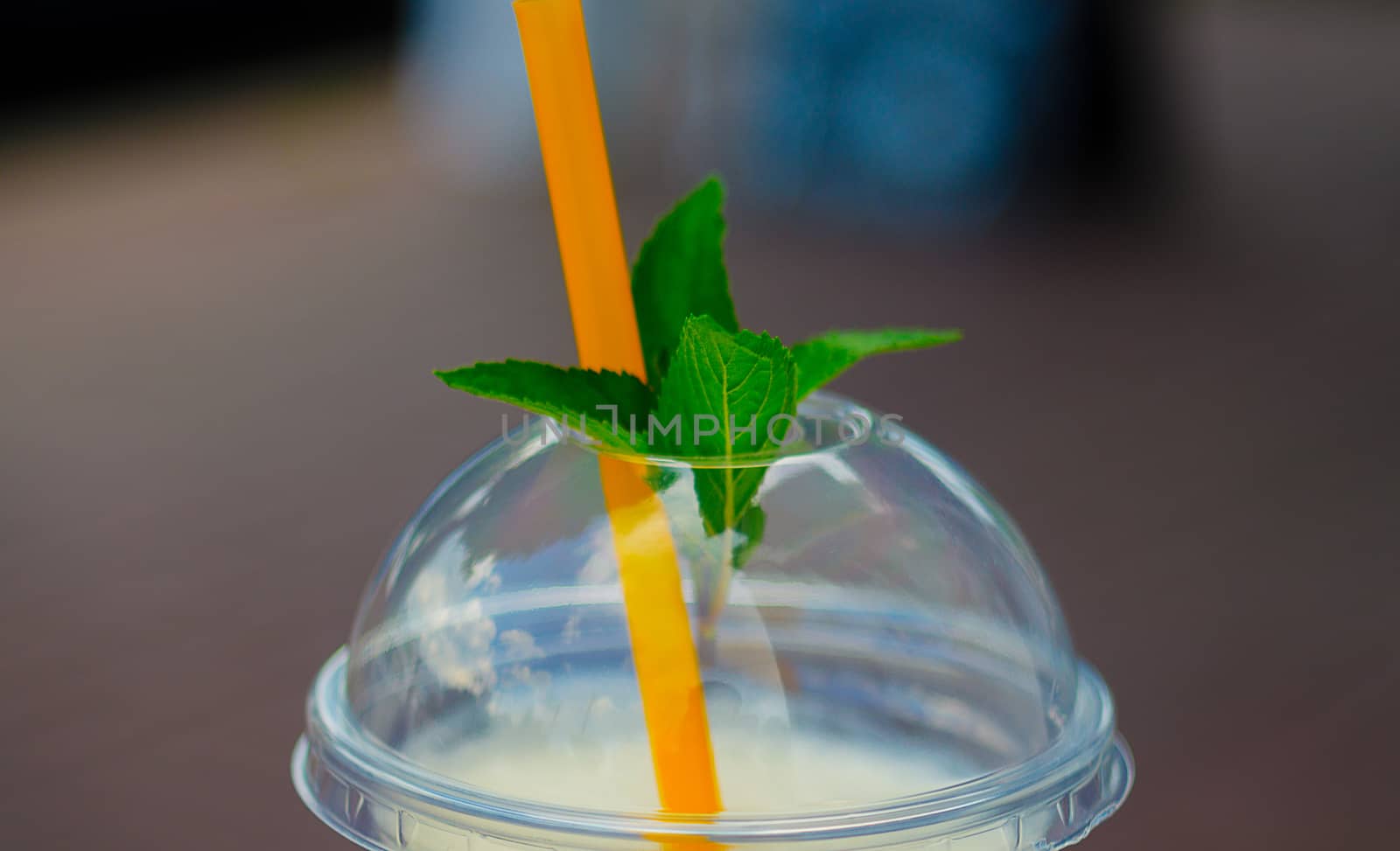 Pina colada cocktail in plactic glass with cover and tubule. Mint leaf on cover. Close-up view.