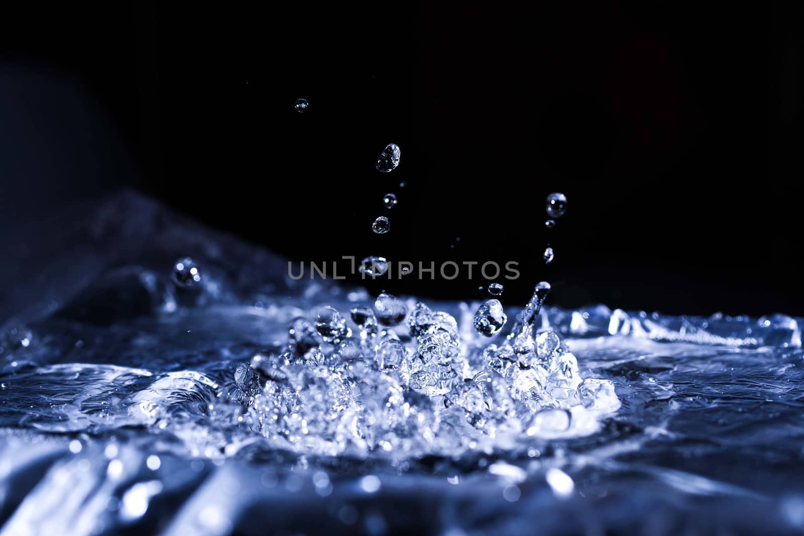 Water drops splashing on acoustic membrane. A lot of drops in air. High frequency of sound waves. Water cloud small drops. Frozen time shot.