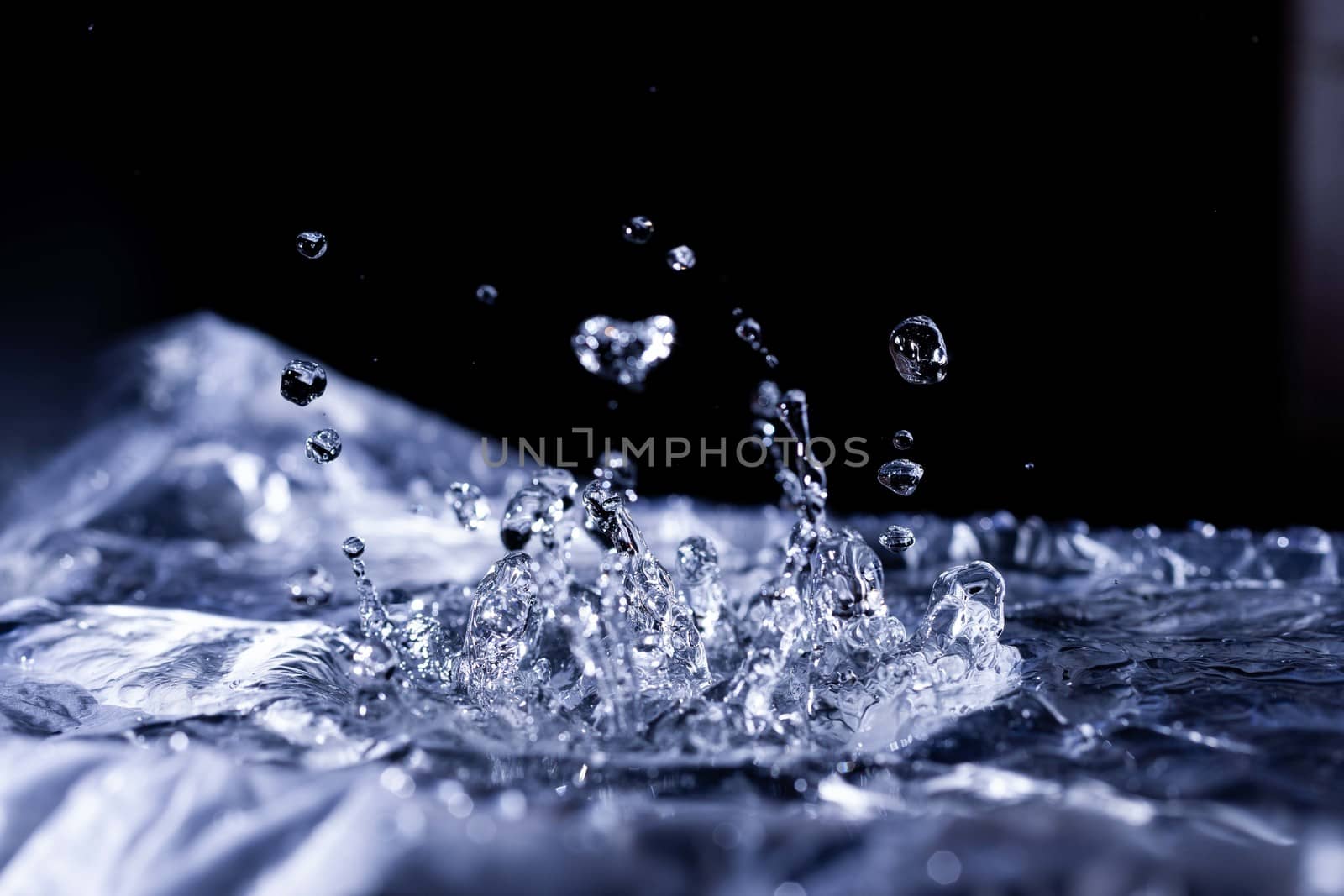 Water drops splashing on acoustic membrane. A lot of drops in air. High frequency of sound waves. Water cloud small drops. Frozen time shot.