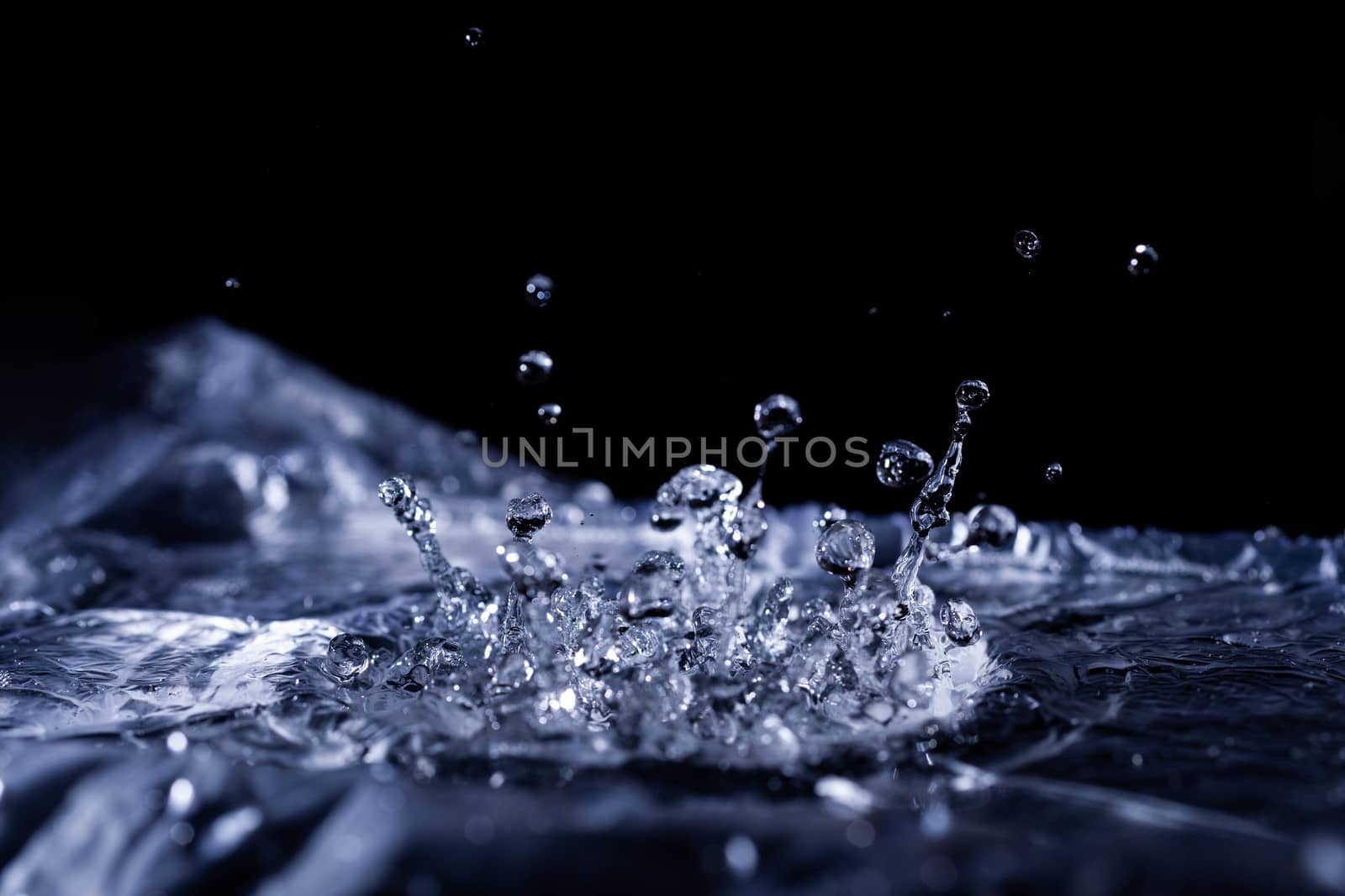 Water drops splashing on acoustic membrane. A lot of drops in air. High frequency of sound waves. Water cloud small drops. Frozen time shot.
