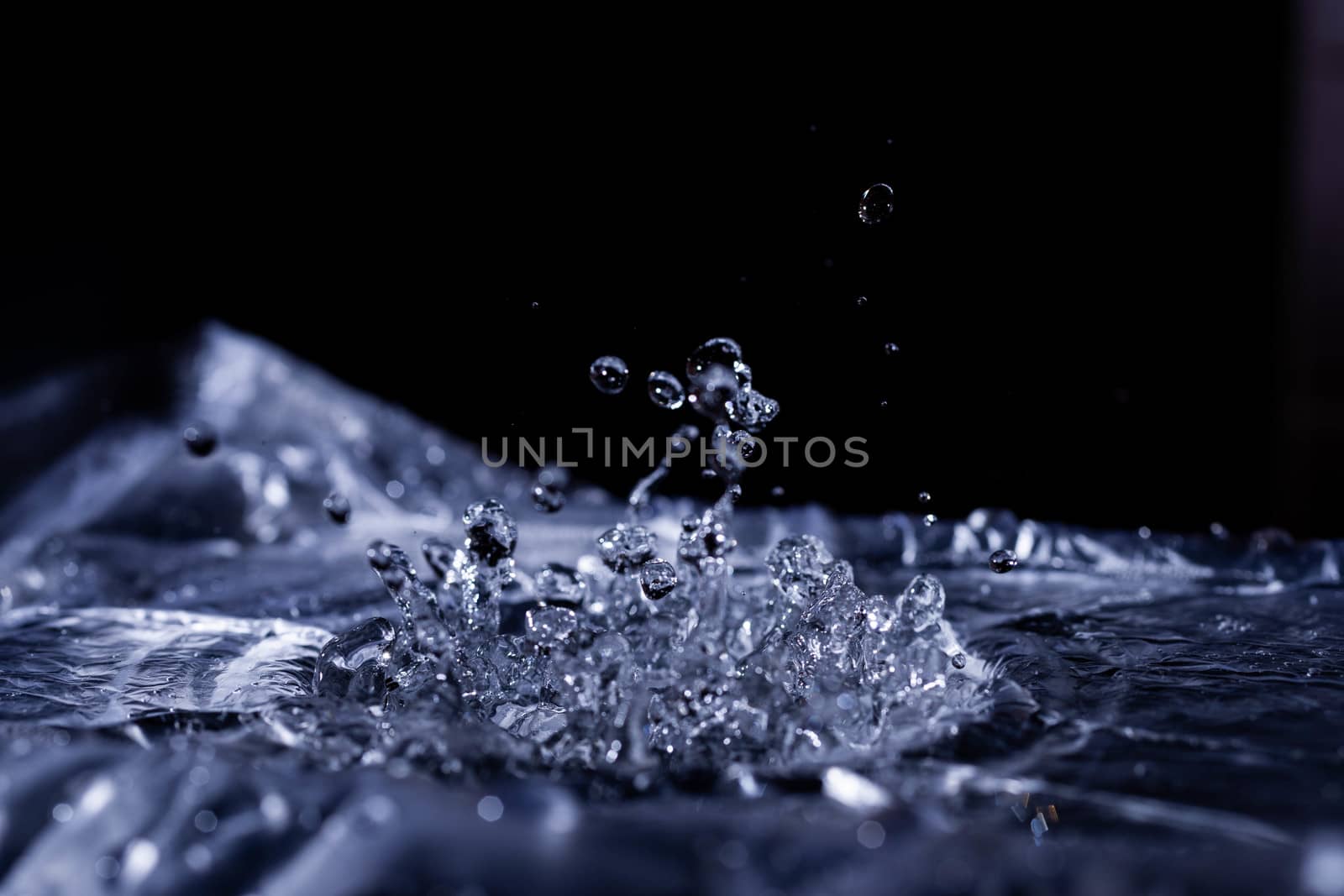 Water drops splashing on acoustic membrane. A lot of drops in air. High frequency of sound waves. Water cloud small drops. Frozen time shot. 
