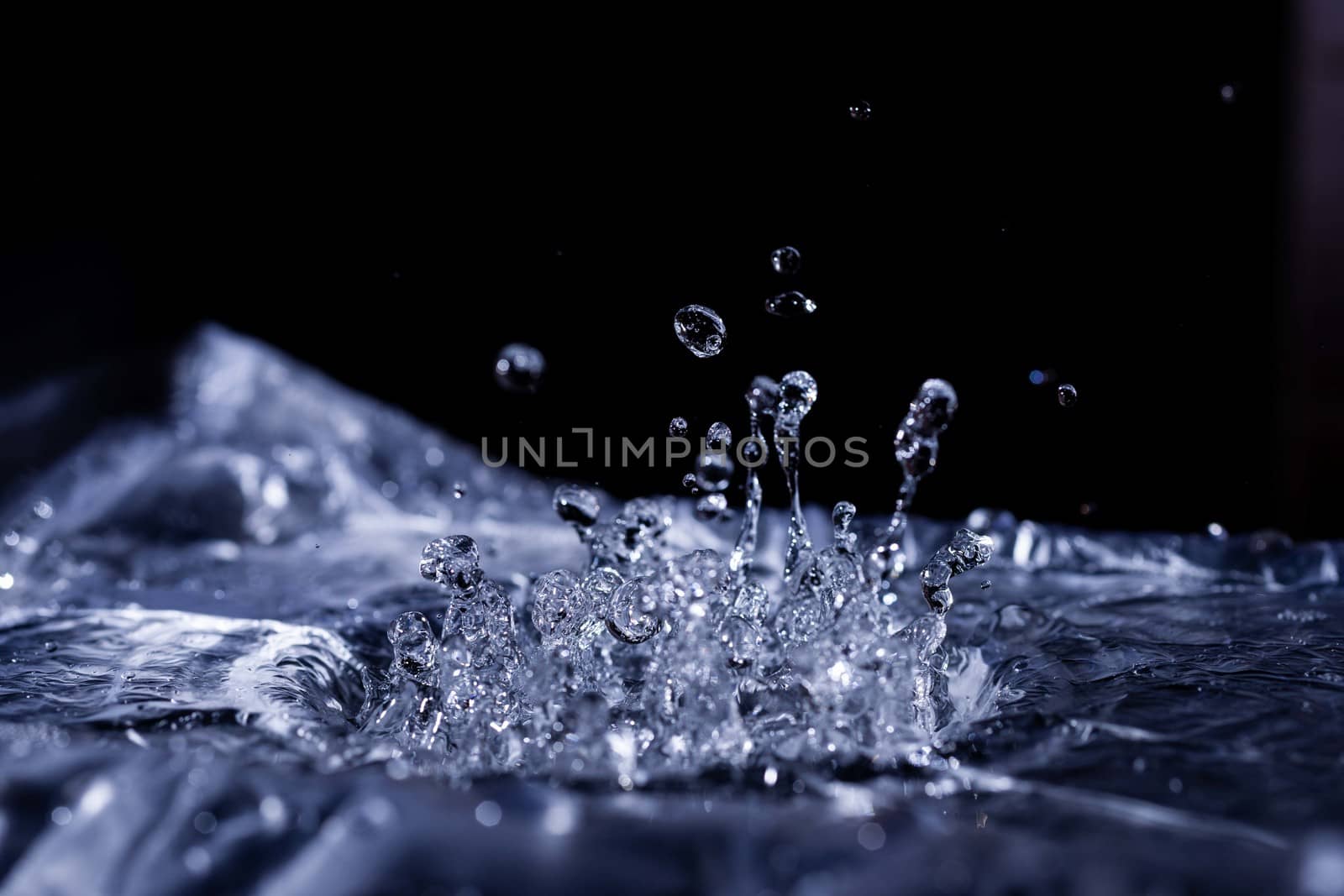 Water drops splashing on acoustic membrane. A lot of drops in air. High frequency of sound waves. Water cloud small drops. Frozen time shot.