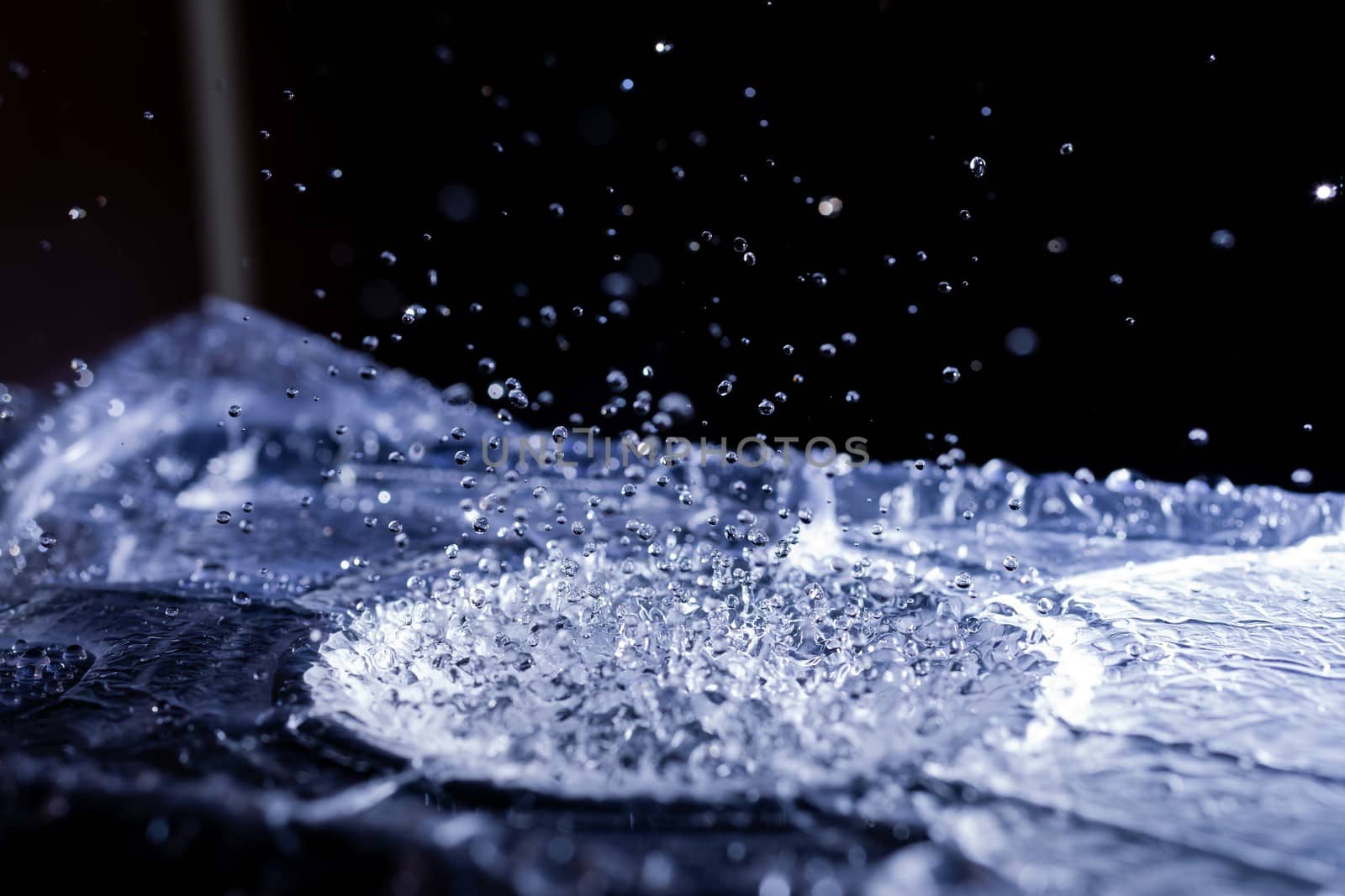 Water drops splashing on acoustic membrane. A lot of drops in air. High frequency of sound waves. Water cloud small drops. Frozen time shot.