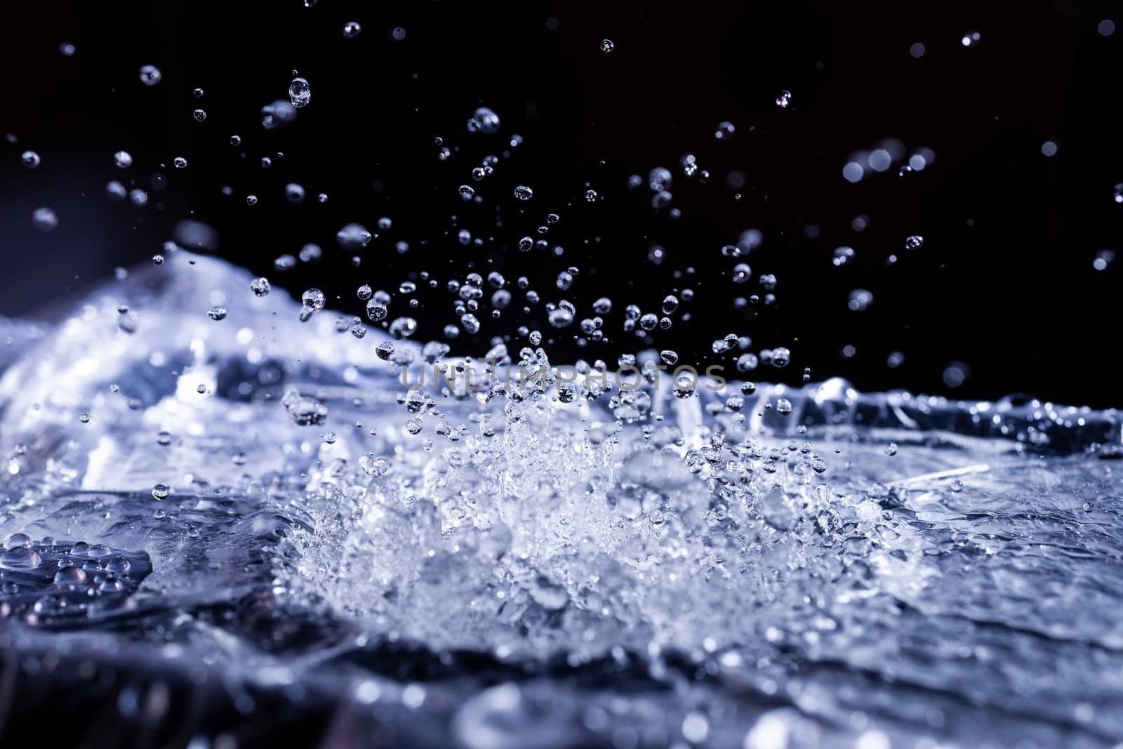 Water drops splashing on acoustic membrane. A lot of drops in air. High frequency of sound waves. Water cloud small drops. Frozen time shot.
