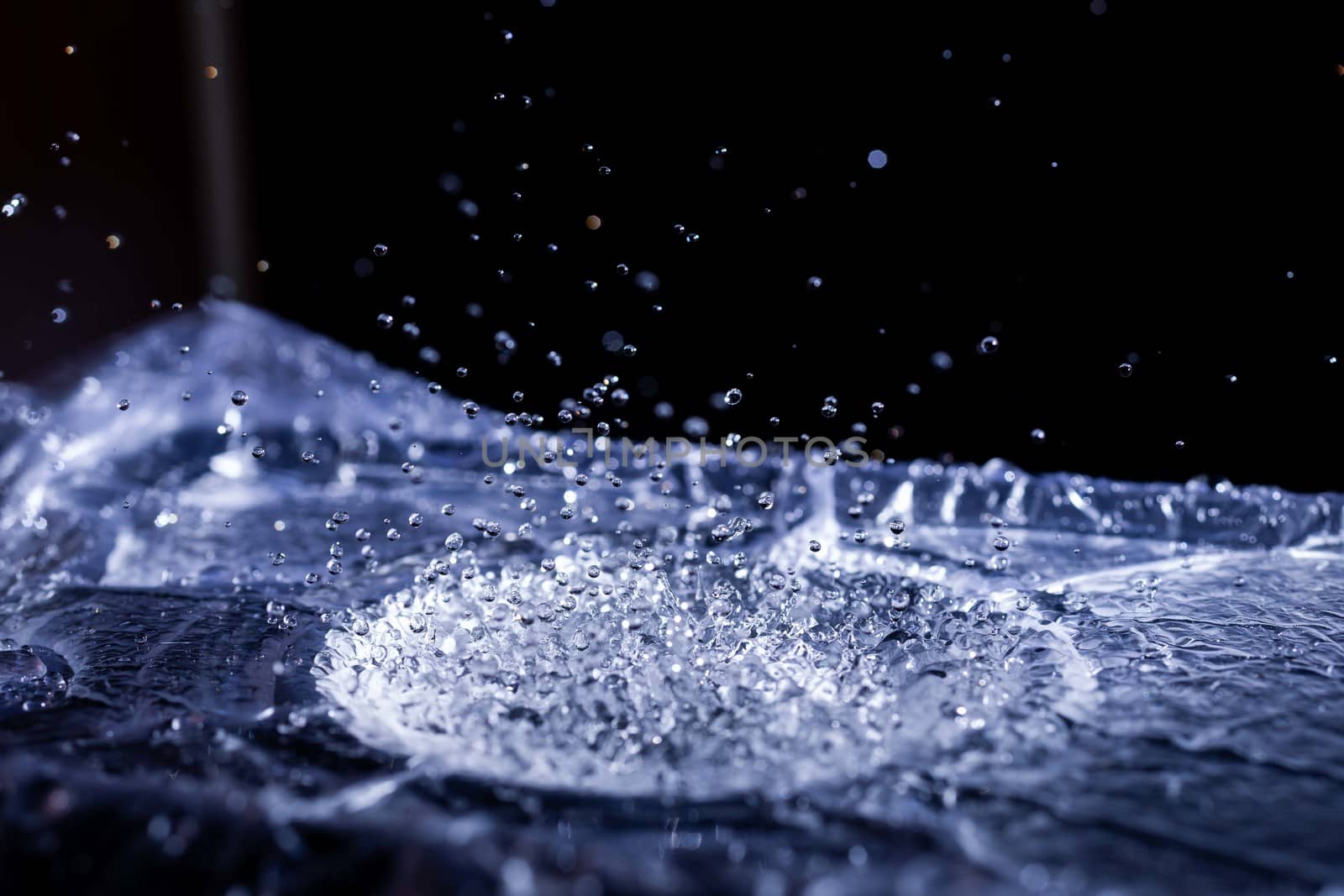 Water drops splashing on acoustic membrane. A lot of drops in air. High frequency of sound waves. Water cloud small drops. Frozen time shot.