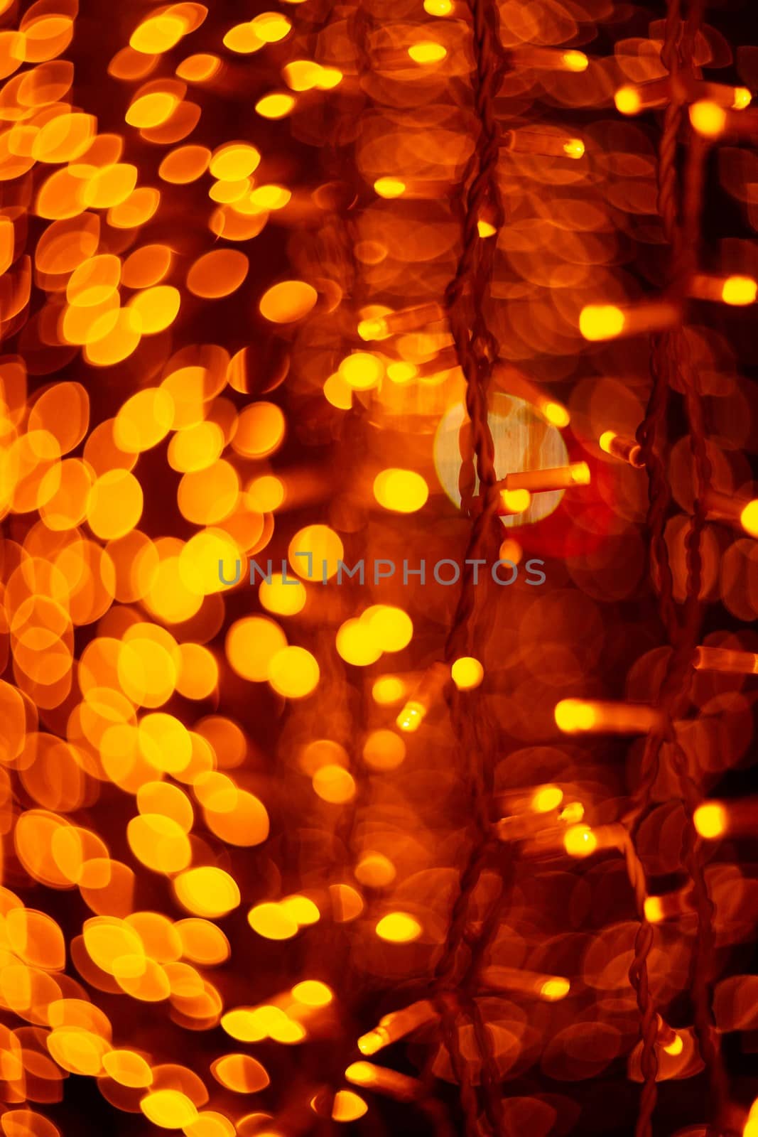 Vertical Christmas garland wall on glass window. Light is orange and defocused. Blurred background, new year mood.