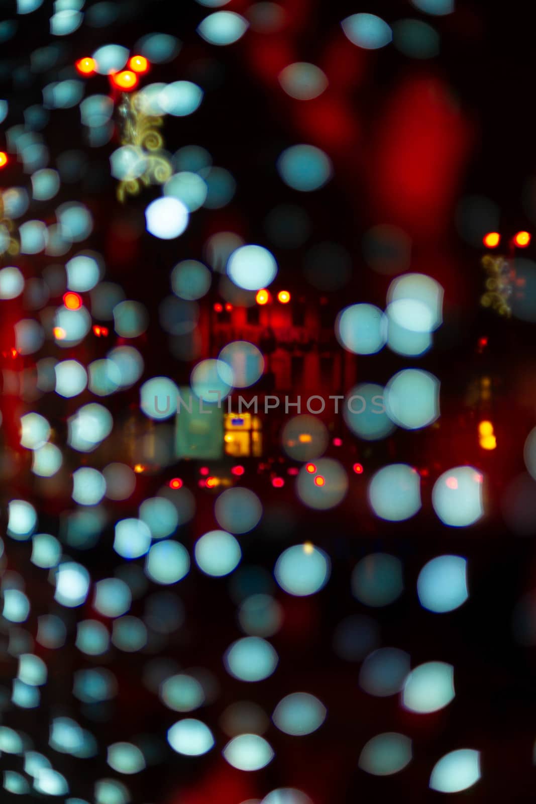 Vertical Christmas garland wall on glass window. Light is white and defocused. Blurred background, new year mood.