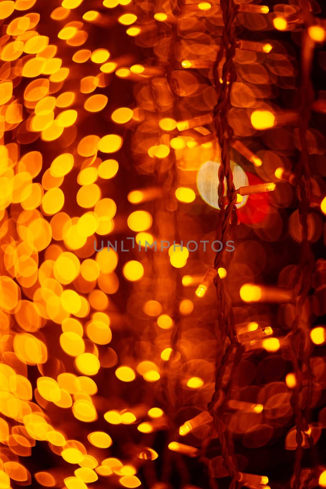 Vertical Christmas garland wall on glass window. Light is orange and defocused. Blurred background, new year mood.