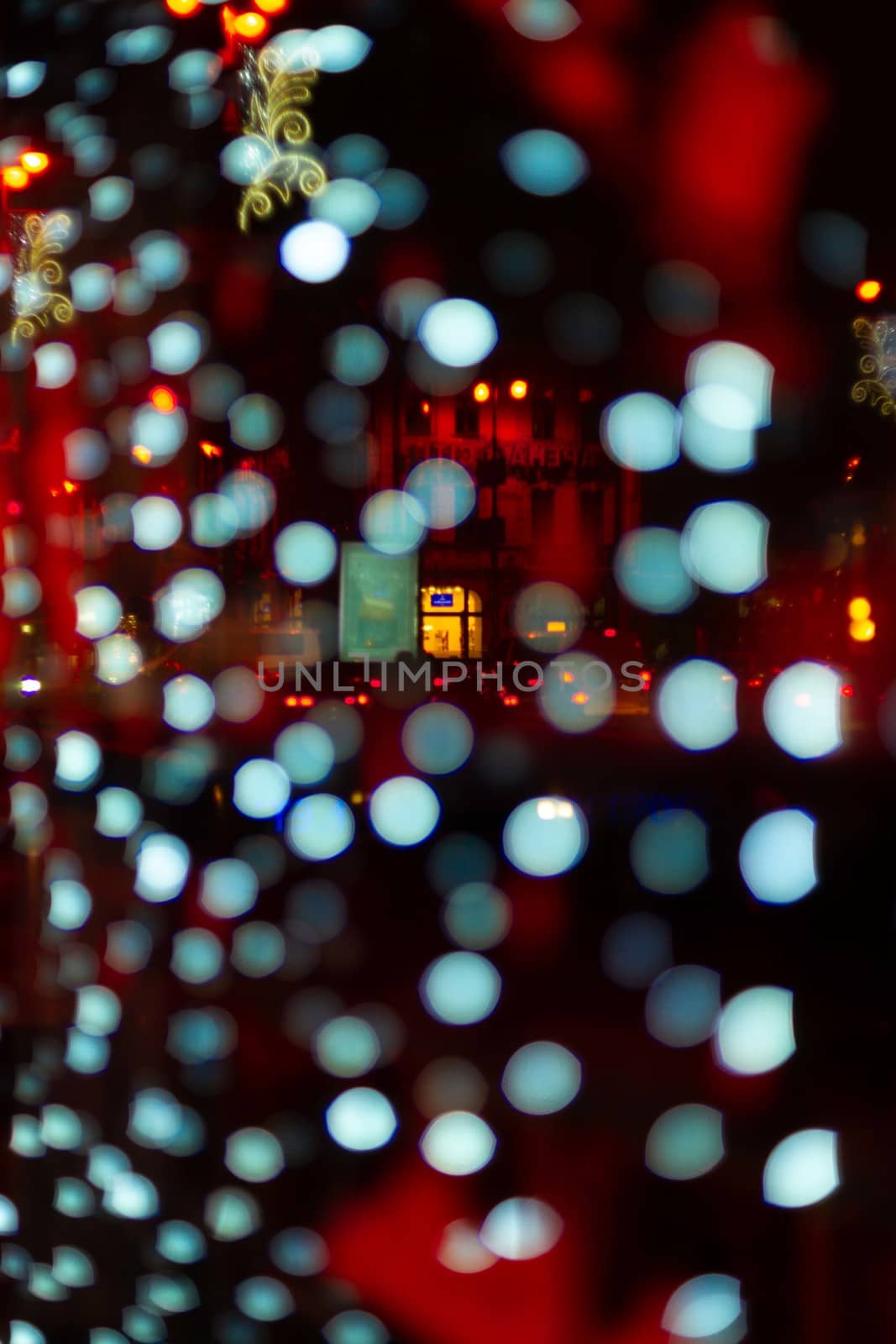 Vertical Christmas garland wall on glass window. Light is white and defocused. Blurred background, new year mood.