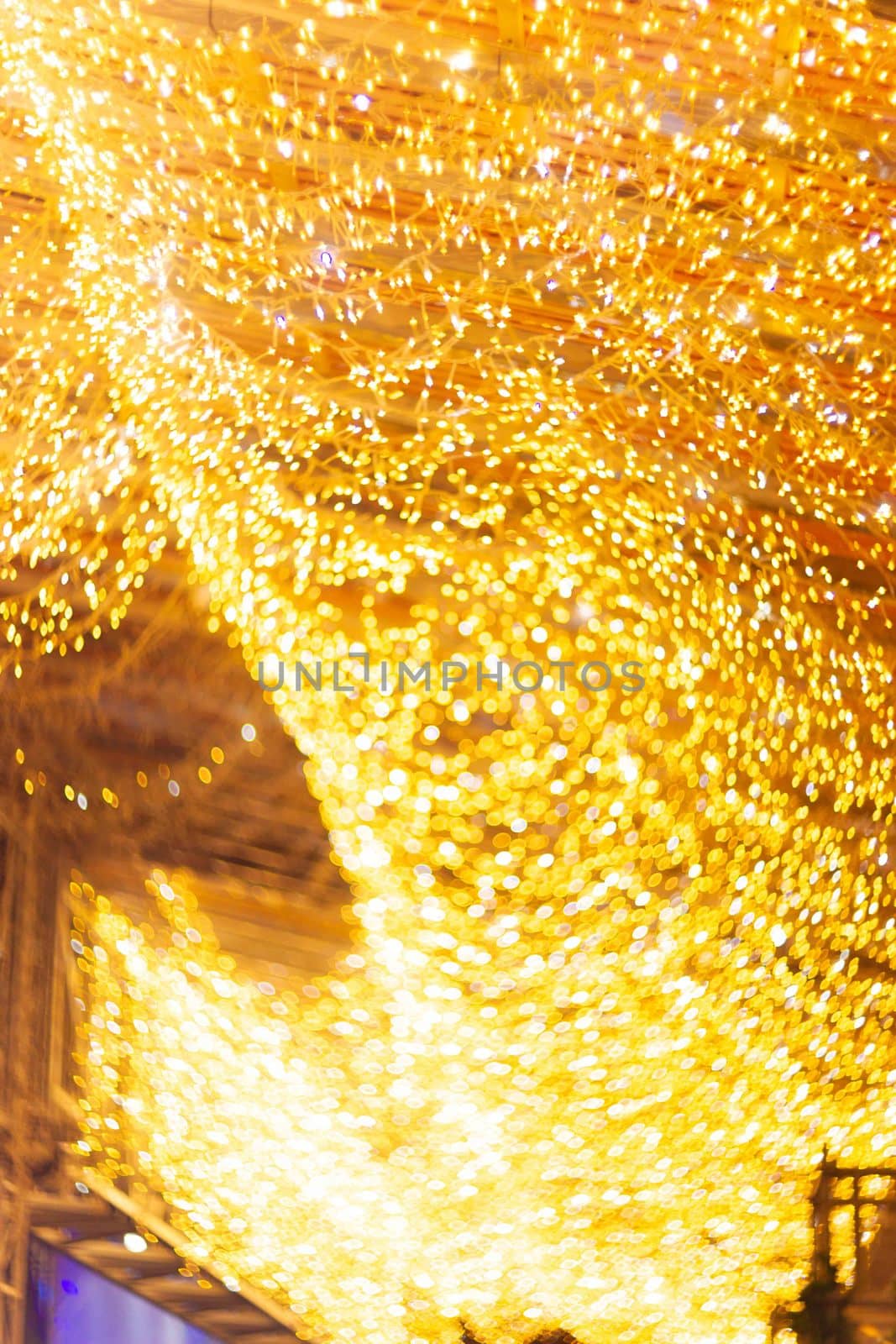 Horizontal Christmas garland wall on glass roof Light is orange and defocused. Blurred background, new year mood. Underexposed low light photo