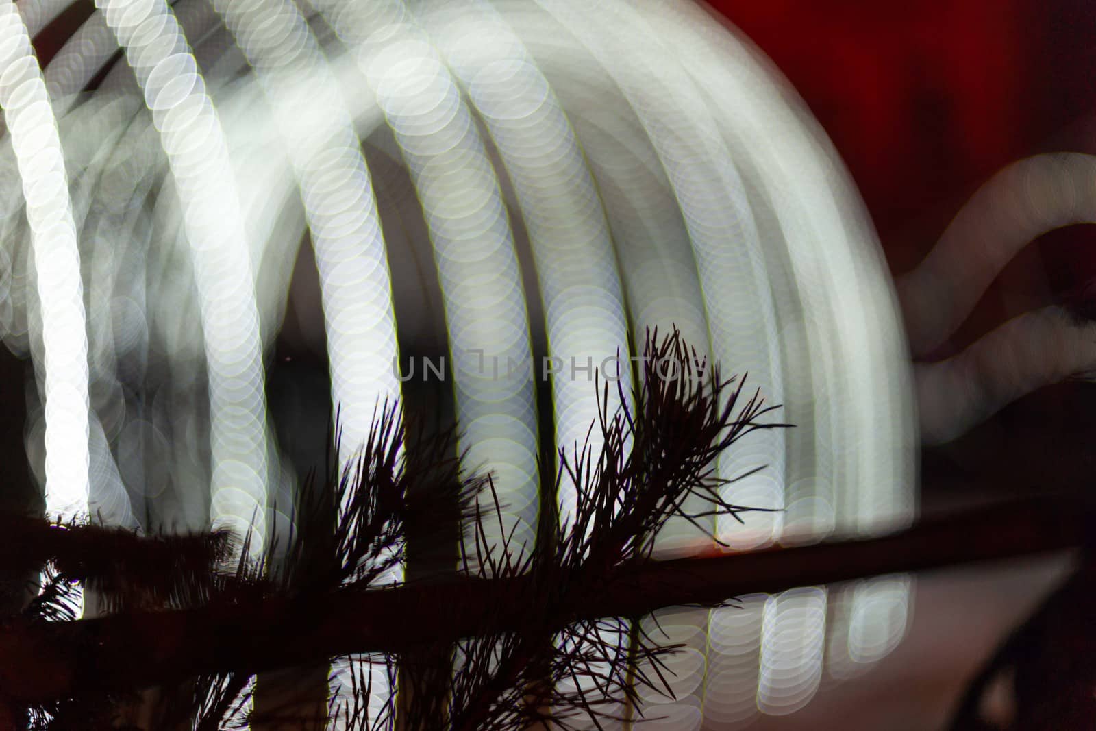 Christmas tree in focus in foreground. Christmas garland on blurred background. Light is light and defocused. Blurred background, new year mood.