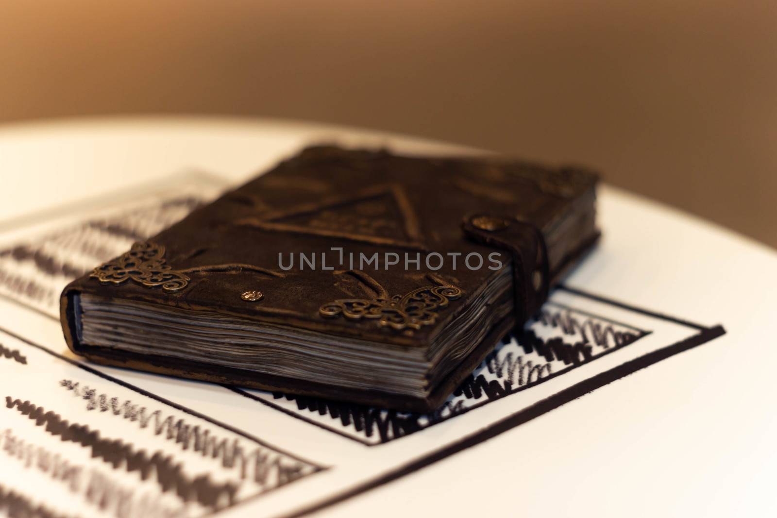 Handmade magic notebook with tower symbol on cover. Leather cover and handmade sheets inside. Very blurred background with soft focus on notebook.