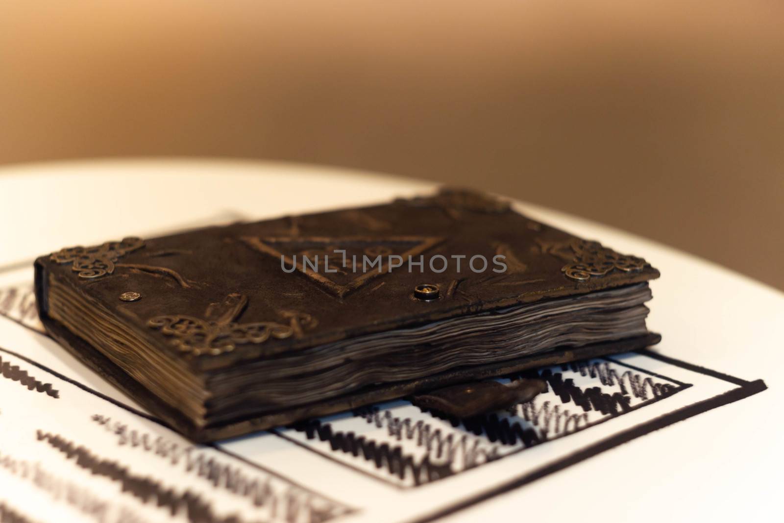Handmade magic notebook with tower symbol on cover. Leather cover and handmade sheets inside. Very blurred background with soft focus on notebook.