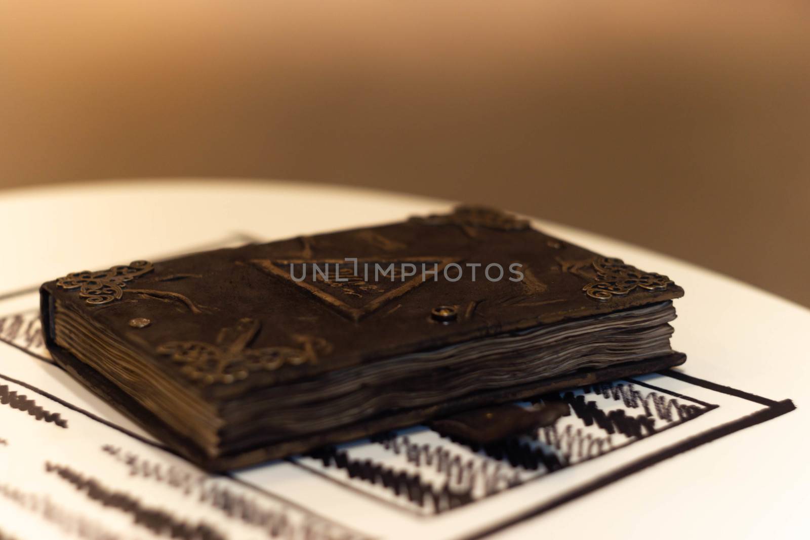 Handmade magic notebook with tower symbol on cover. Leather cover and handmade sheets inside. Very blurred background with soft focus on notebook.